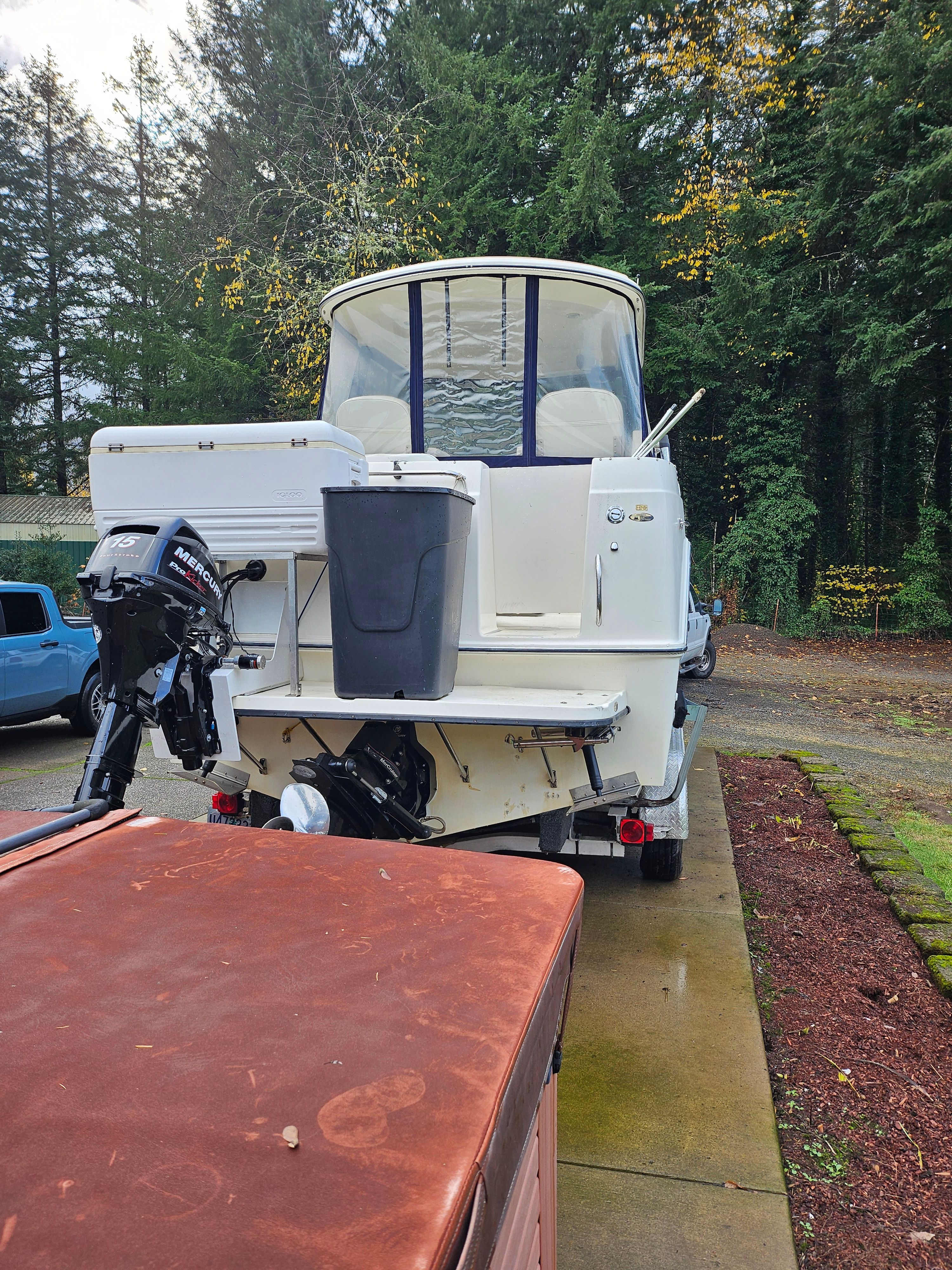 A 2005 Bayliner 242 Ceara on a trailer, surrounded by trees.