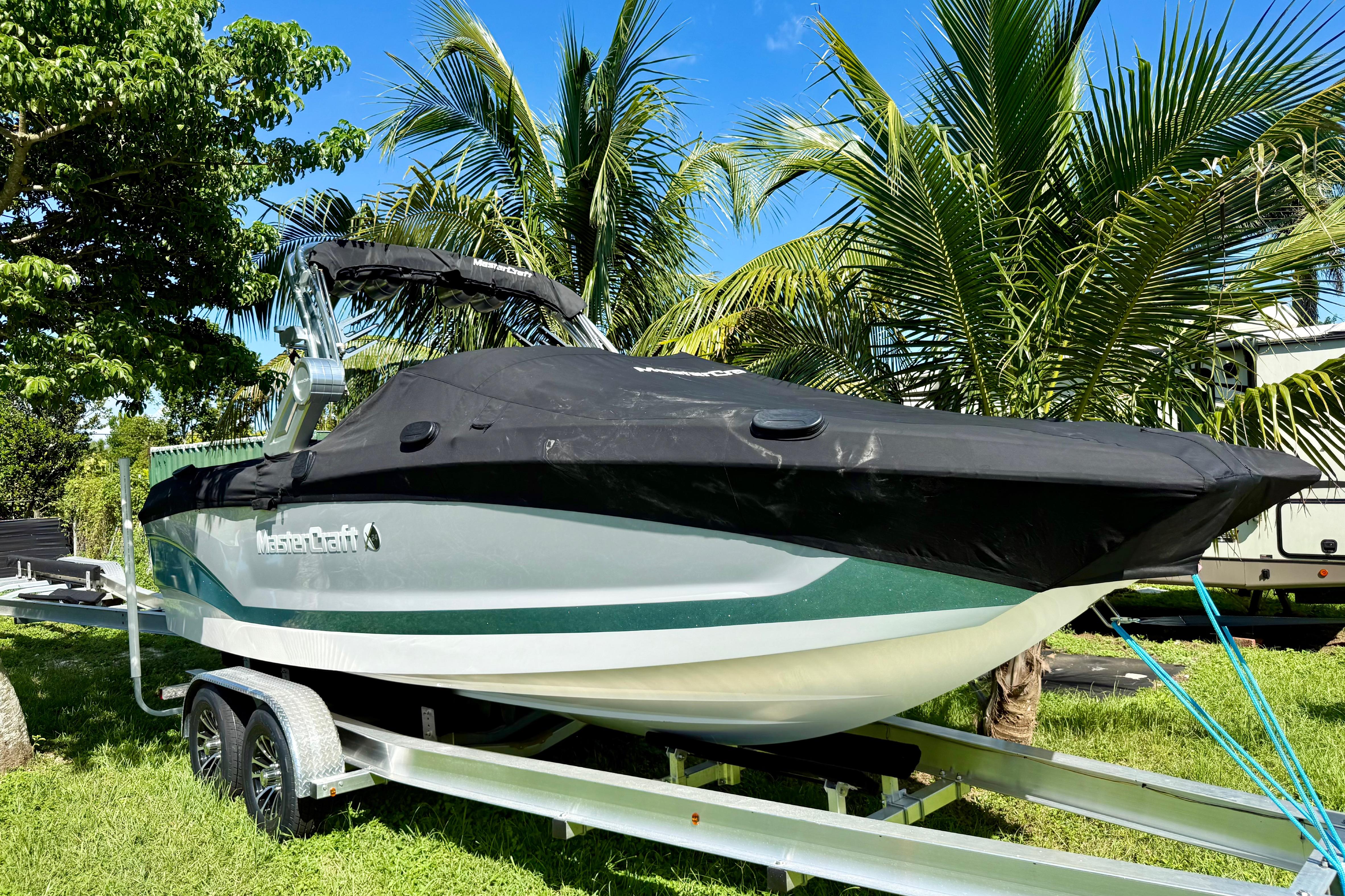 2023 MasterCraft X24 boat on trailer, surrounded by palm trees.