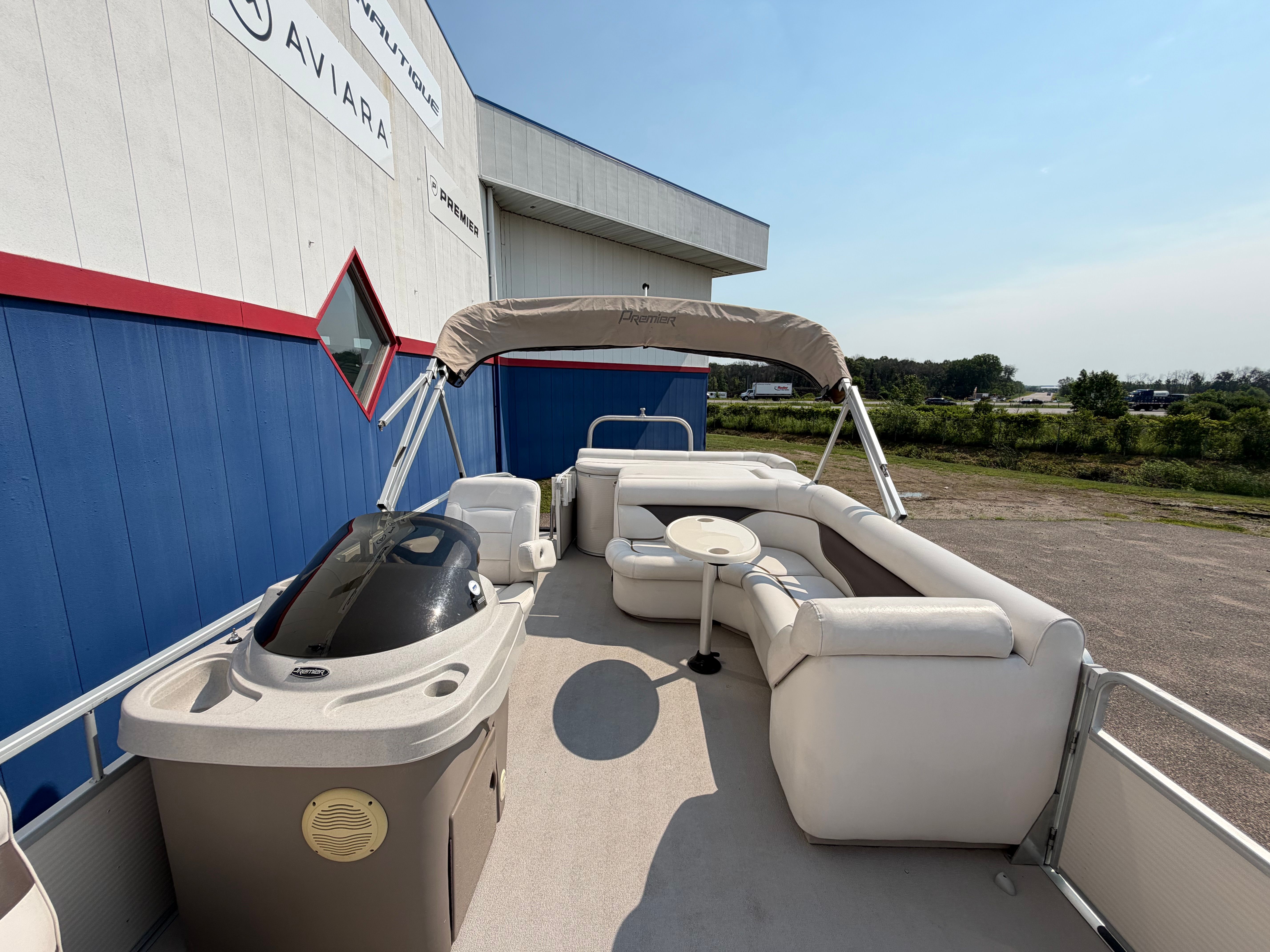 A 2007 Premier 225 Sunsation pontoon boat with beige bimini top and white seating.