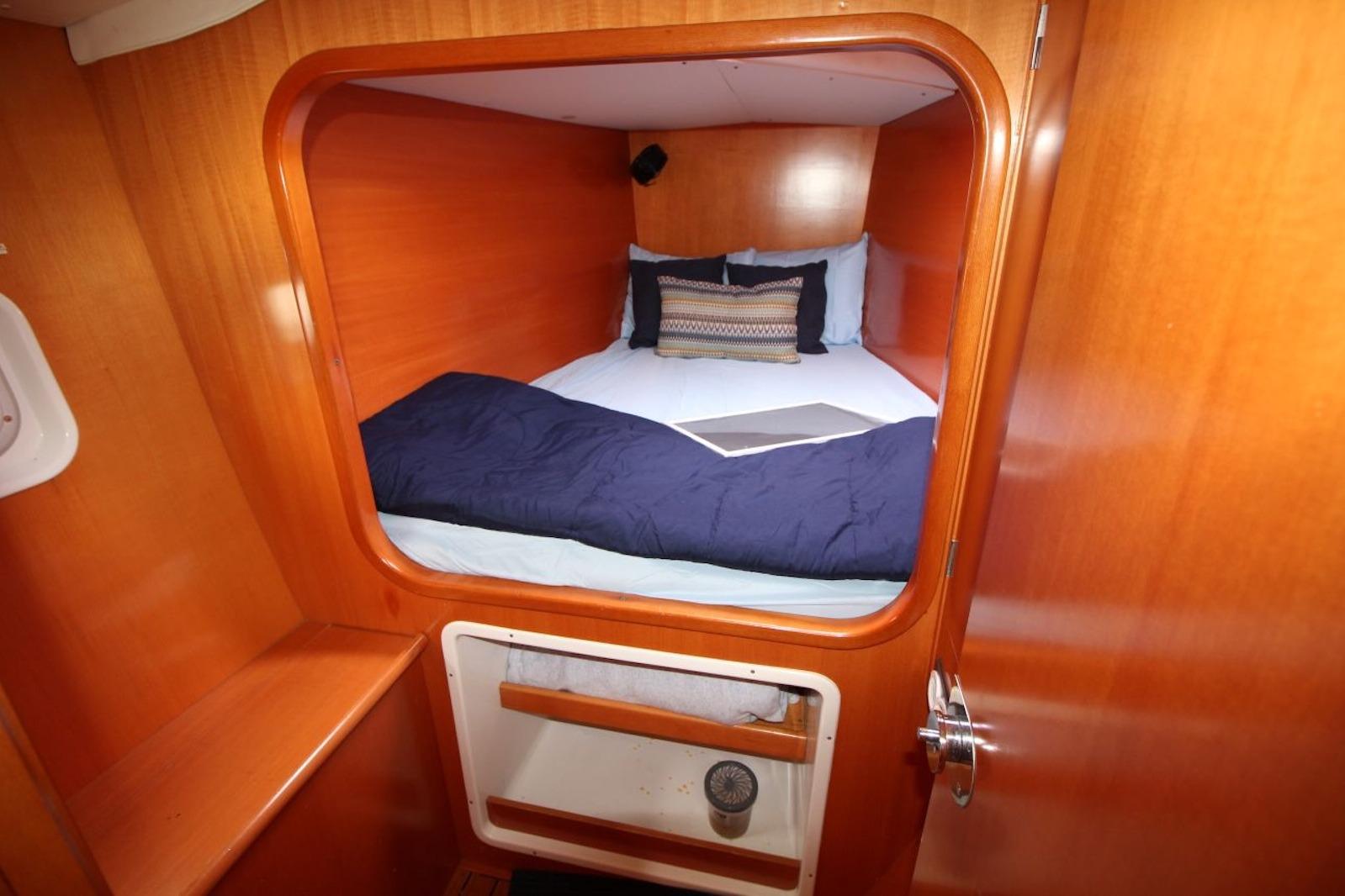 Cozy cabin interior of 2004 Lagoon 380 catamaran with wooden finish and comfortable bedding.