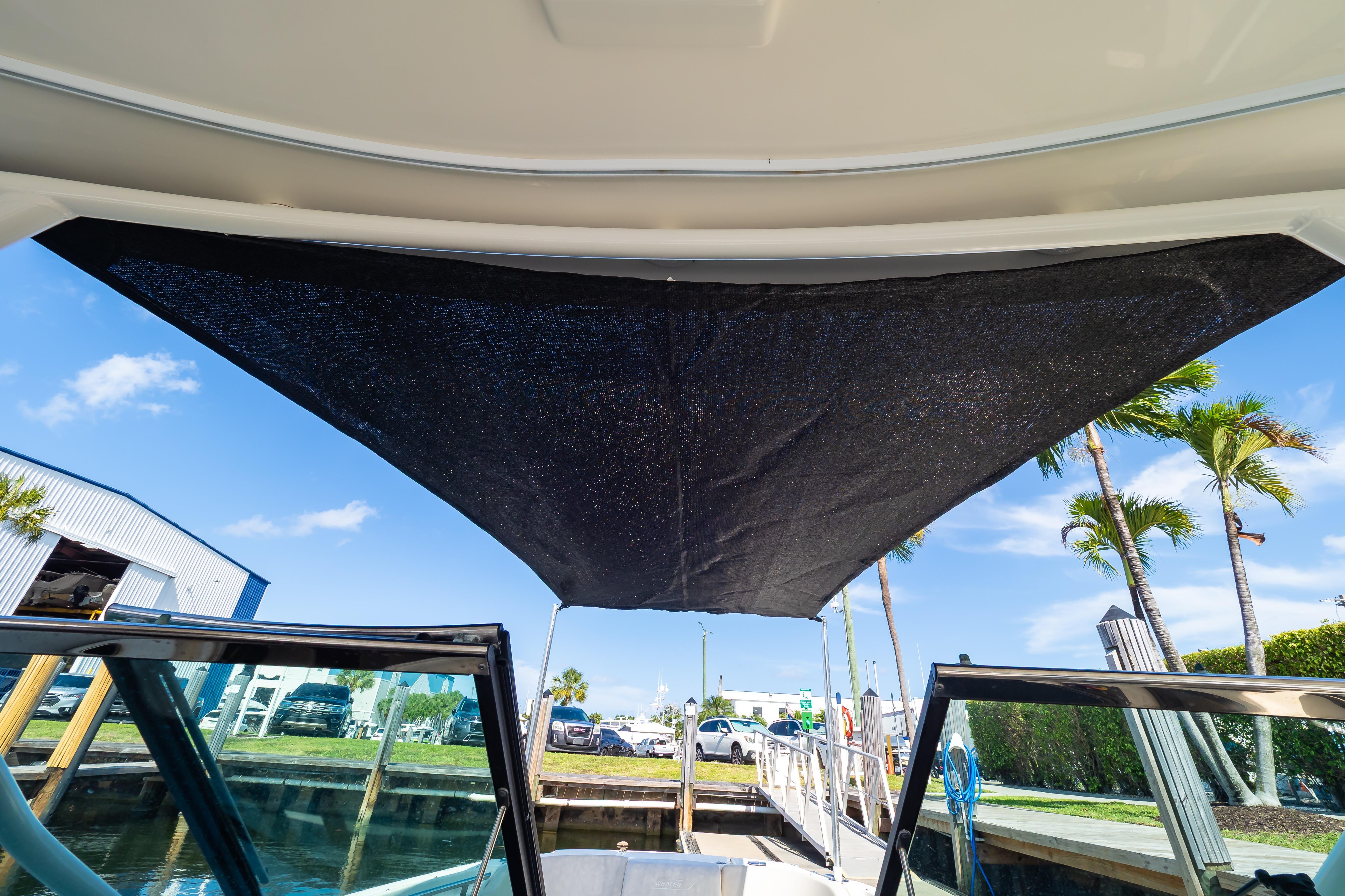 2019 Boston Whaler 270 Vantage boat with sunshade, docked under clear blue sky.