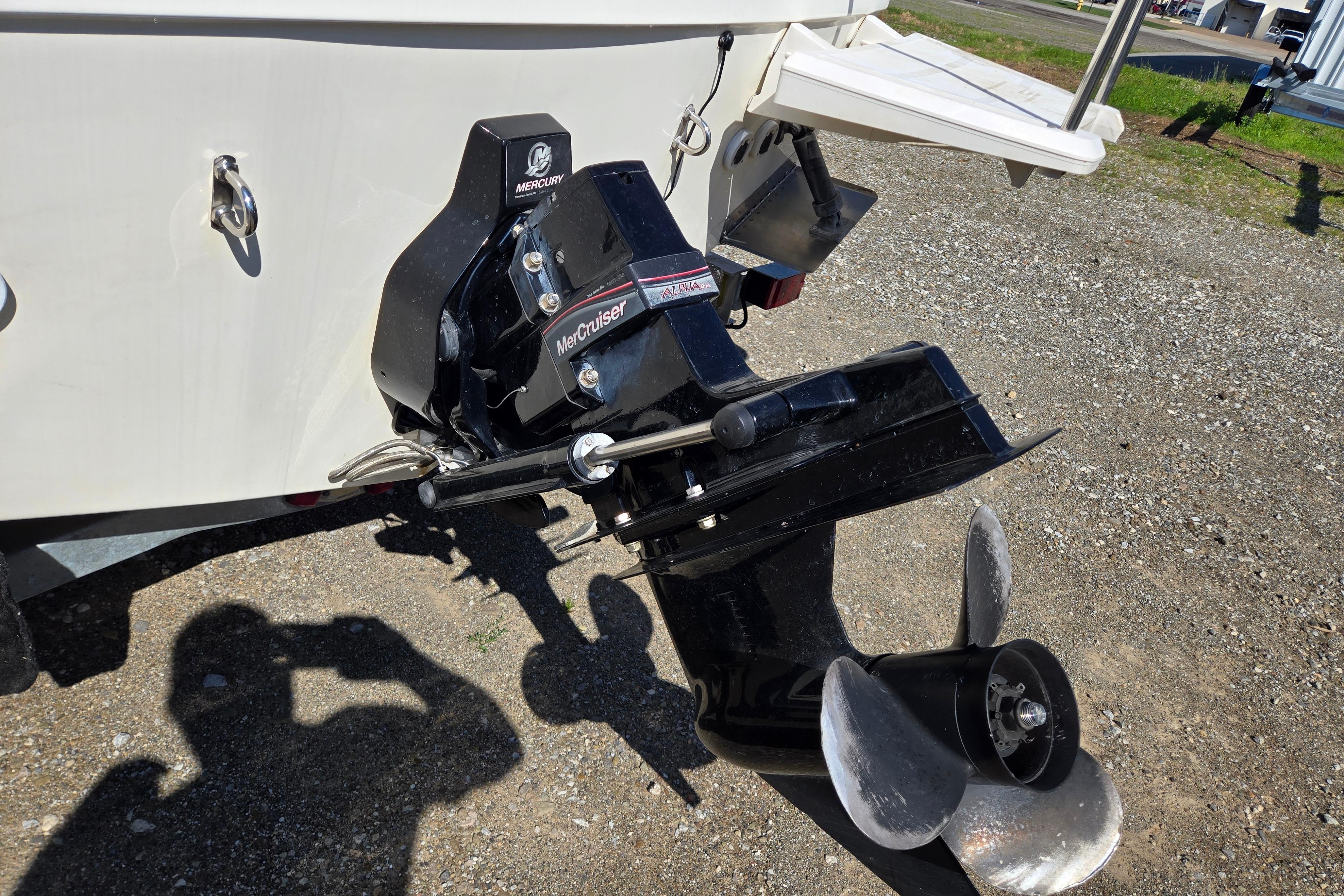 Bayliner 222 Classic 2006 boat with MerCruiser engine and propeller, parked on gravel.