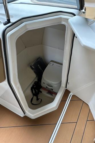 2024 Bayliner DX 2250 boat storage compartment with portable toilet and accessories.