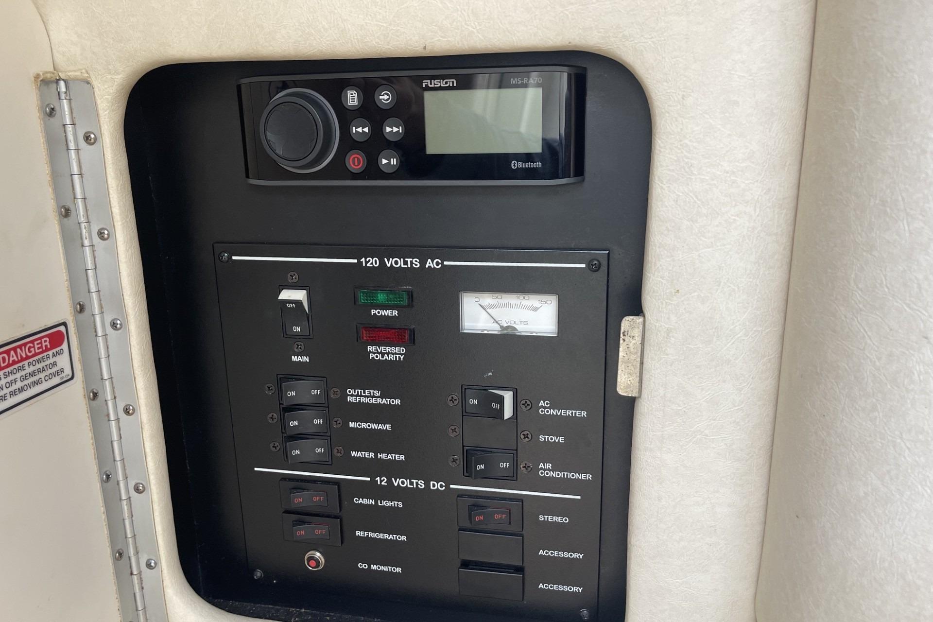 Control panel of a 2000 Sea Ray Sundancer 260 boat with electrical switches and stereo system.