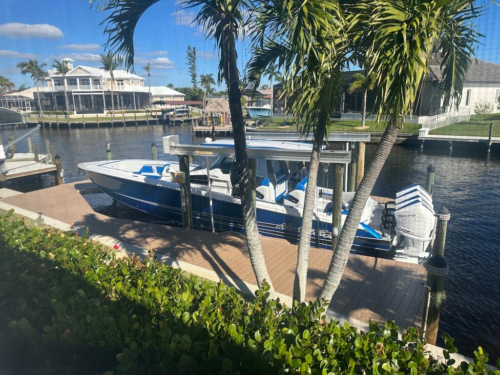 2024 Nor-Tech 400 Supersport boat docked by a canal with palm trees.
