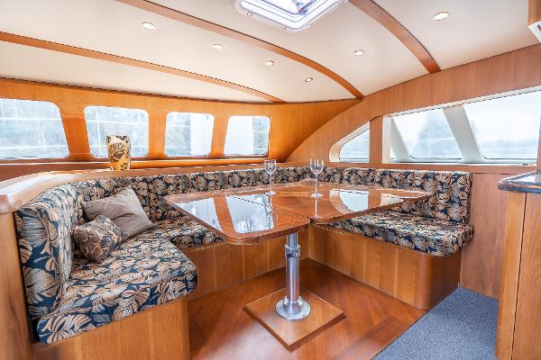 Luxurious interior of 2025 Shuttleworth 52 AeroRig yacht with elegant seating and wooden table.