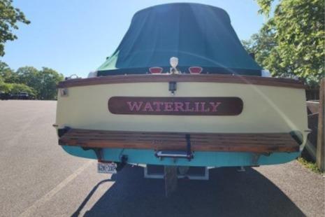 1985 Wasque Down East Cruiser "Waterlily" parked, rear view with cover, sunny day.