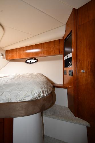 Interior of 2010 Cruisers Yachts 390 Sports Coupe, featuring a cozy bed and wooden cabinetry.