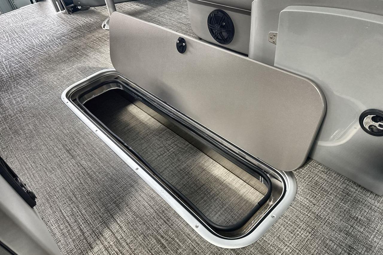 2026 Landau Island Breeze 23F boat interior storage compartment with open hatch on carpeted floor.
