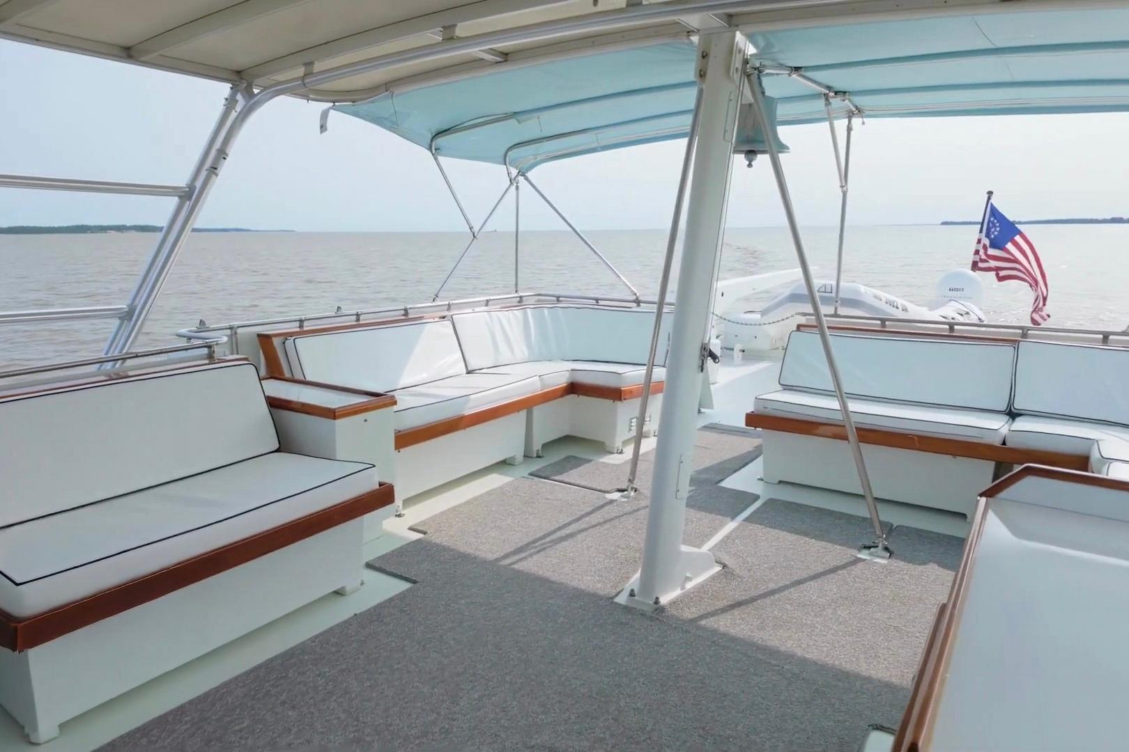 Spacious deck of 1980 Hatteras 70 Motor Yacht with seating and American flag.