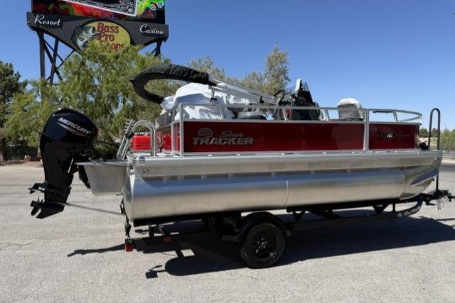 2026 Sun Tracker Bass Buggy 16 XL Select pontoon boat with Mercury engine, parked outdoors.