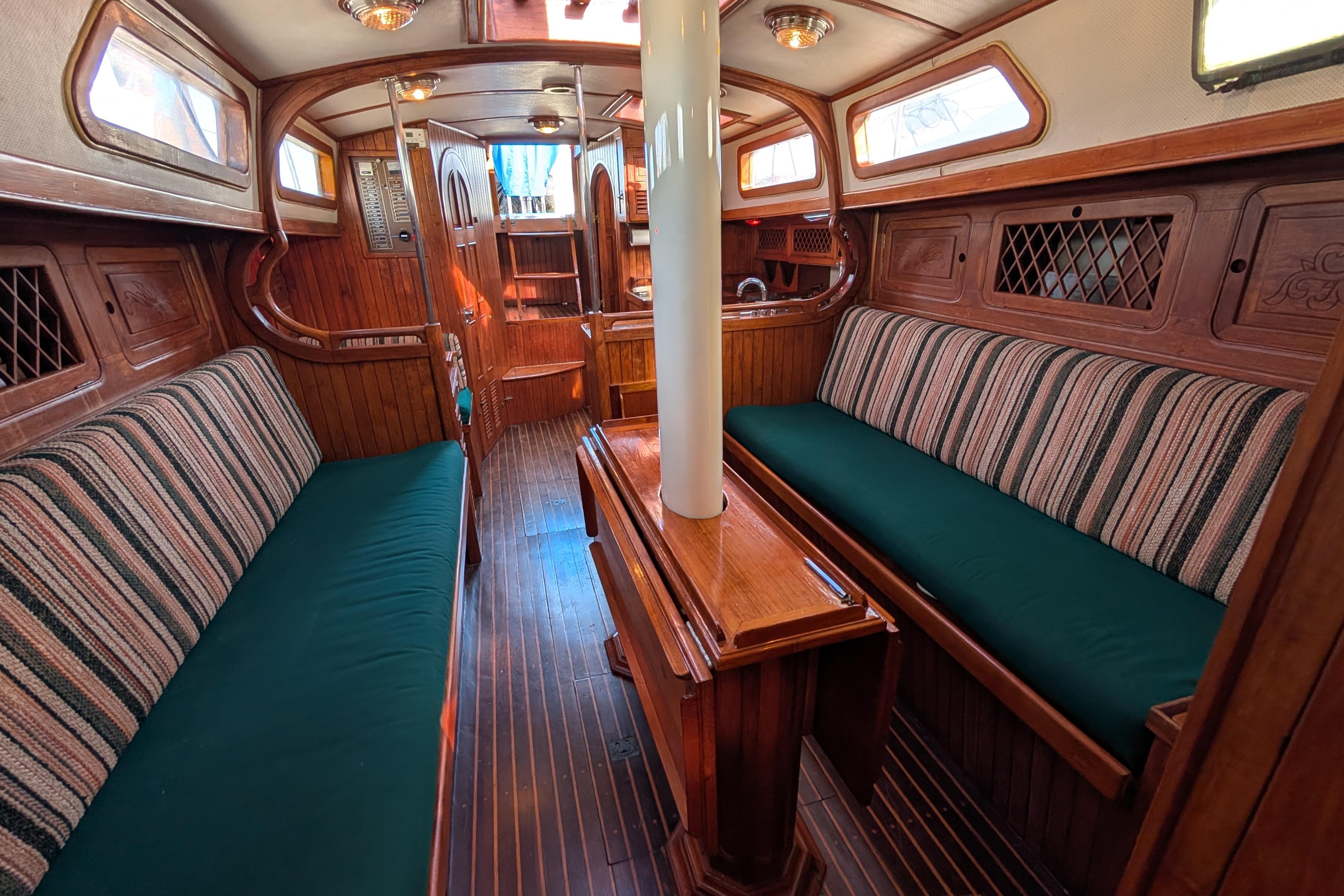 Interior of 1983 Robert Perry 41 sailboat with wooden furnishings and striped upholstery.