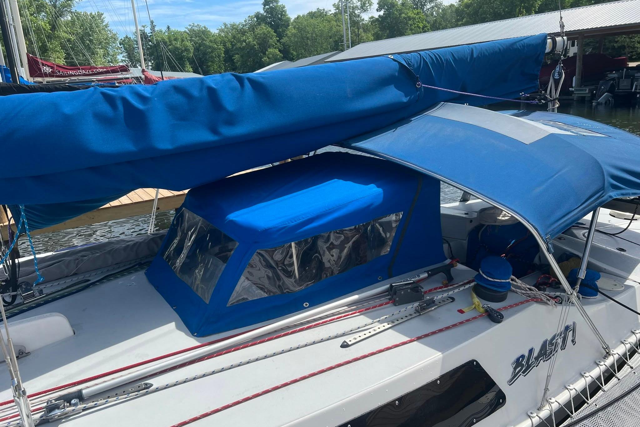 1993 Corsair F-27 sailboat with blue canopy and covered cockpit, docked at marina.