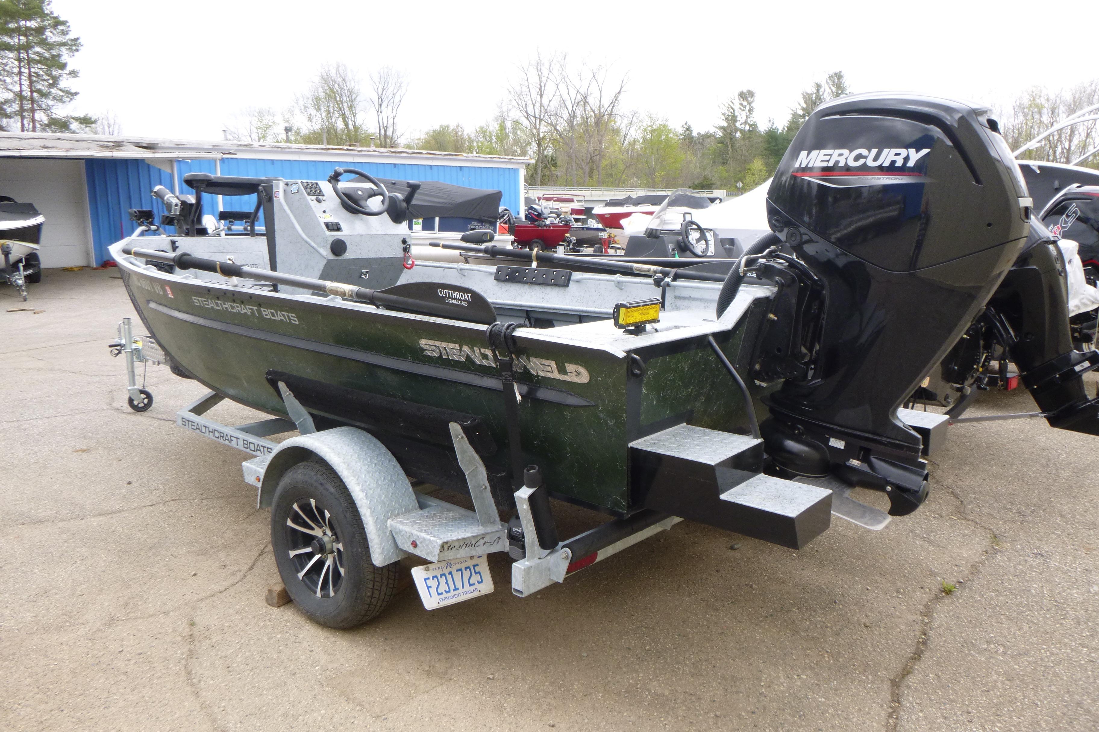 2025 StealthCraft 16 StealthWeld boat with Mercury engine on trailer, parked outdoors.