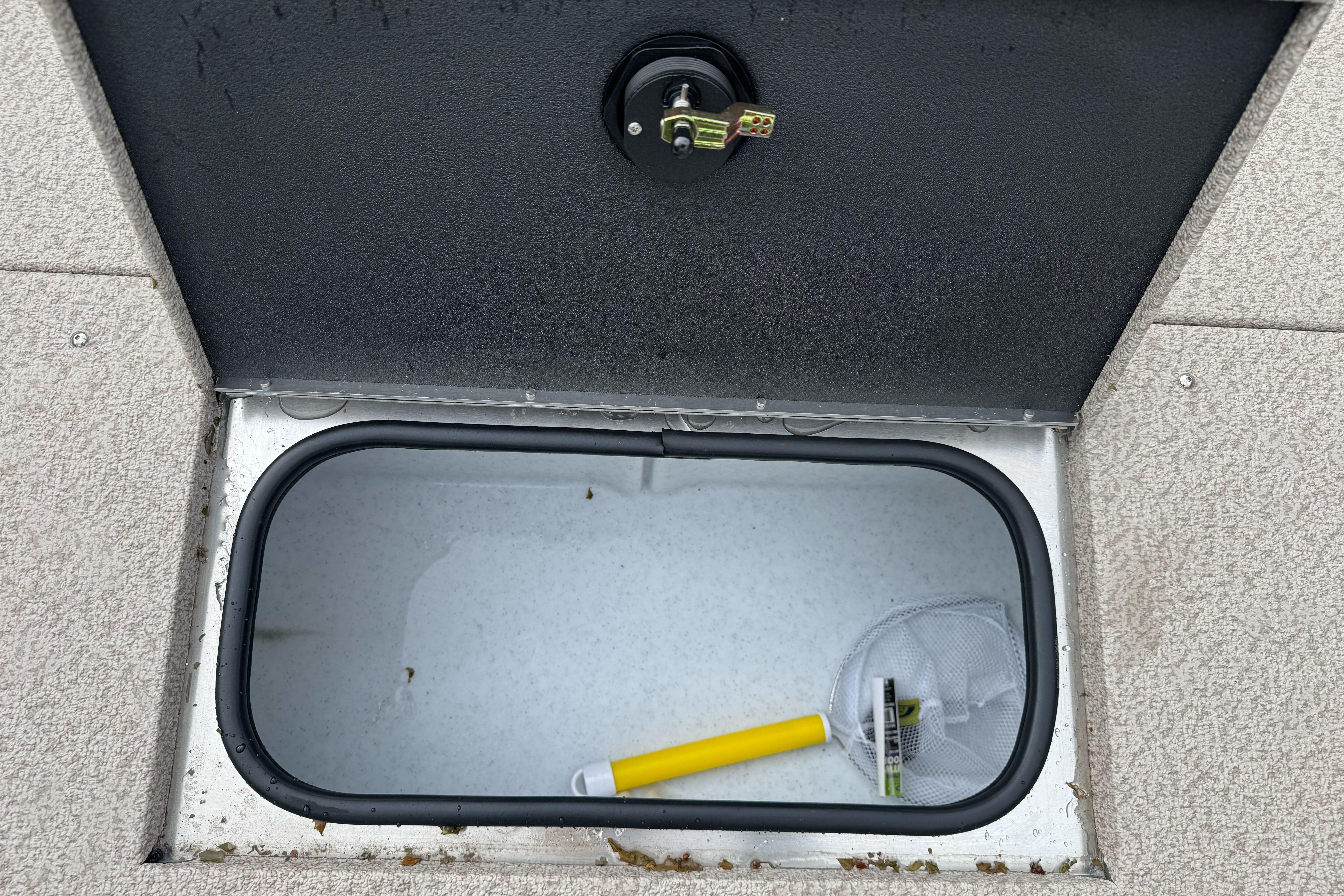 Open storage compartment in 2026 Lund 2075 Alaskan SS boat with net and handle inside.
