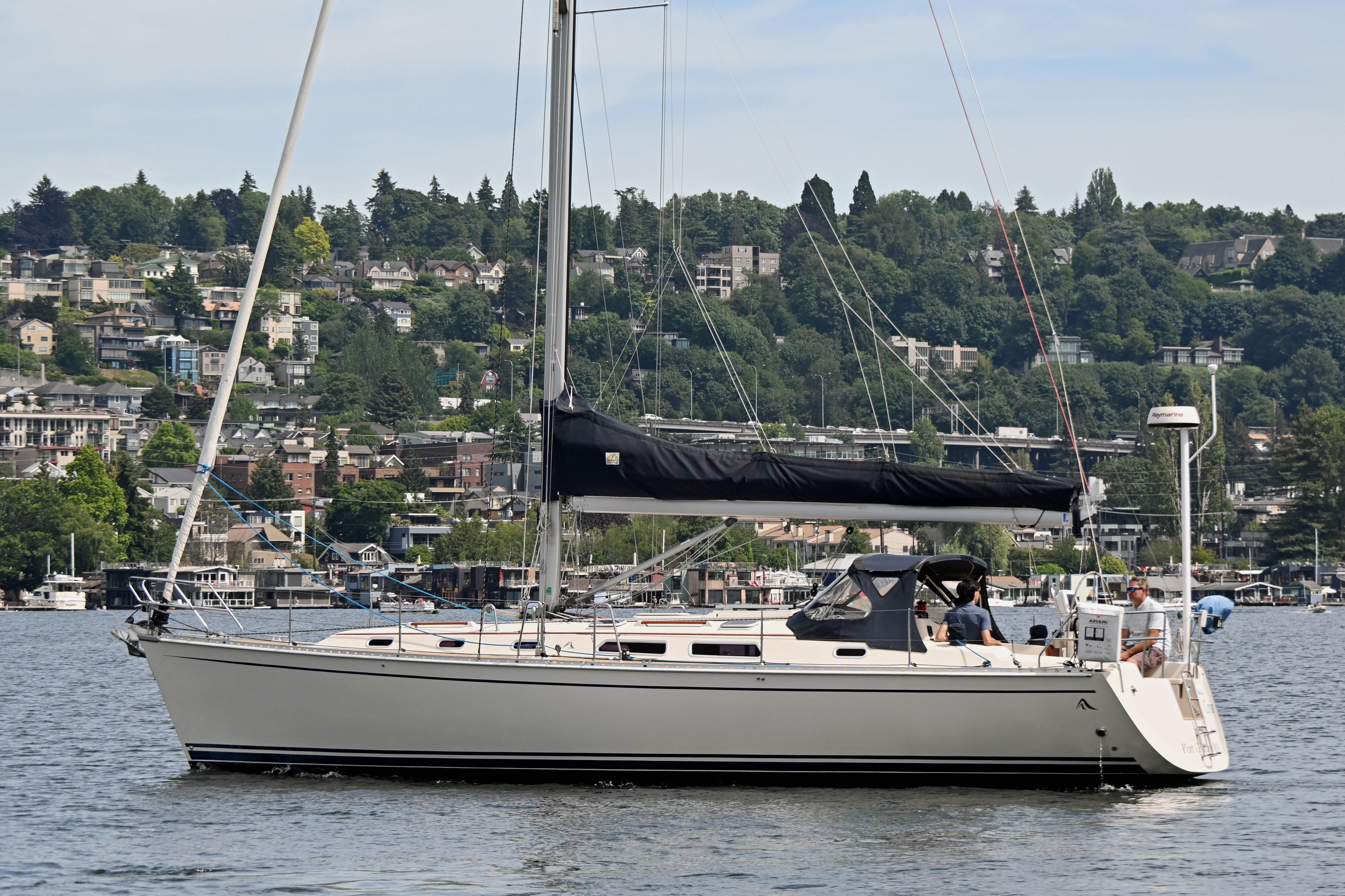 2004 Hanse 411 sailboat on a calm lake with a scenic hillside backdrop.