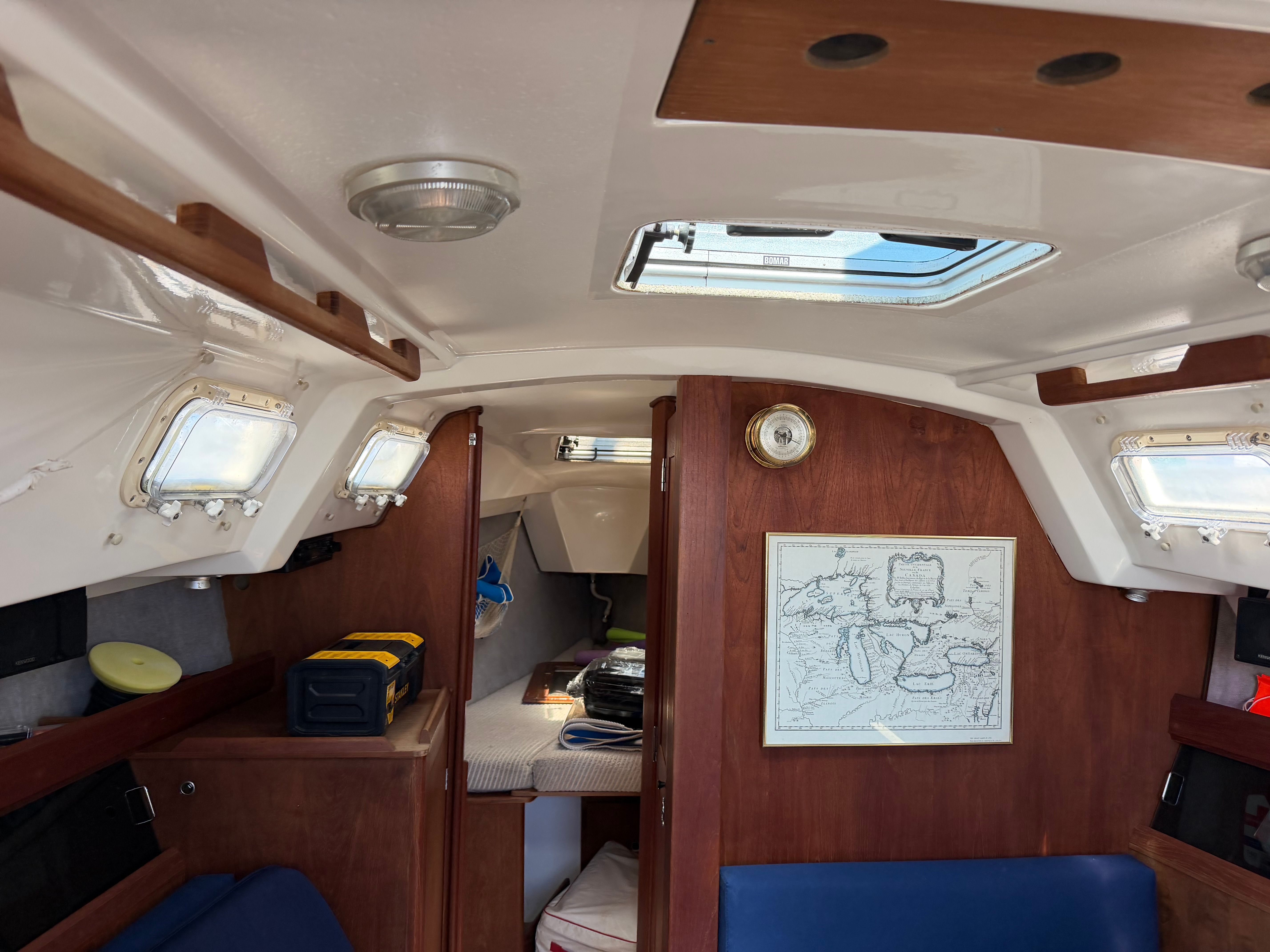 Interior of a sailboat with wooden walls and blue cushions.