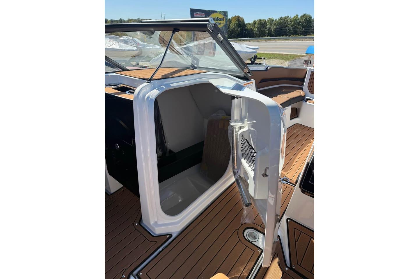 2026 Yamaha Boats 252SD interior with open storage compartment and sleek wooden flooring.