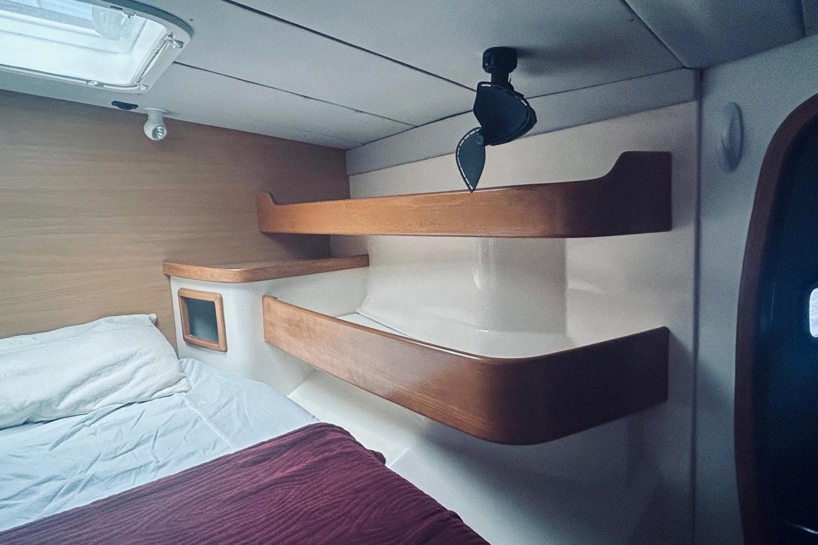 Interior cabin of a 2001 Robertson & Caine Leopard yacht with wooden shelves and bedding.