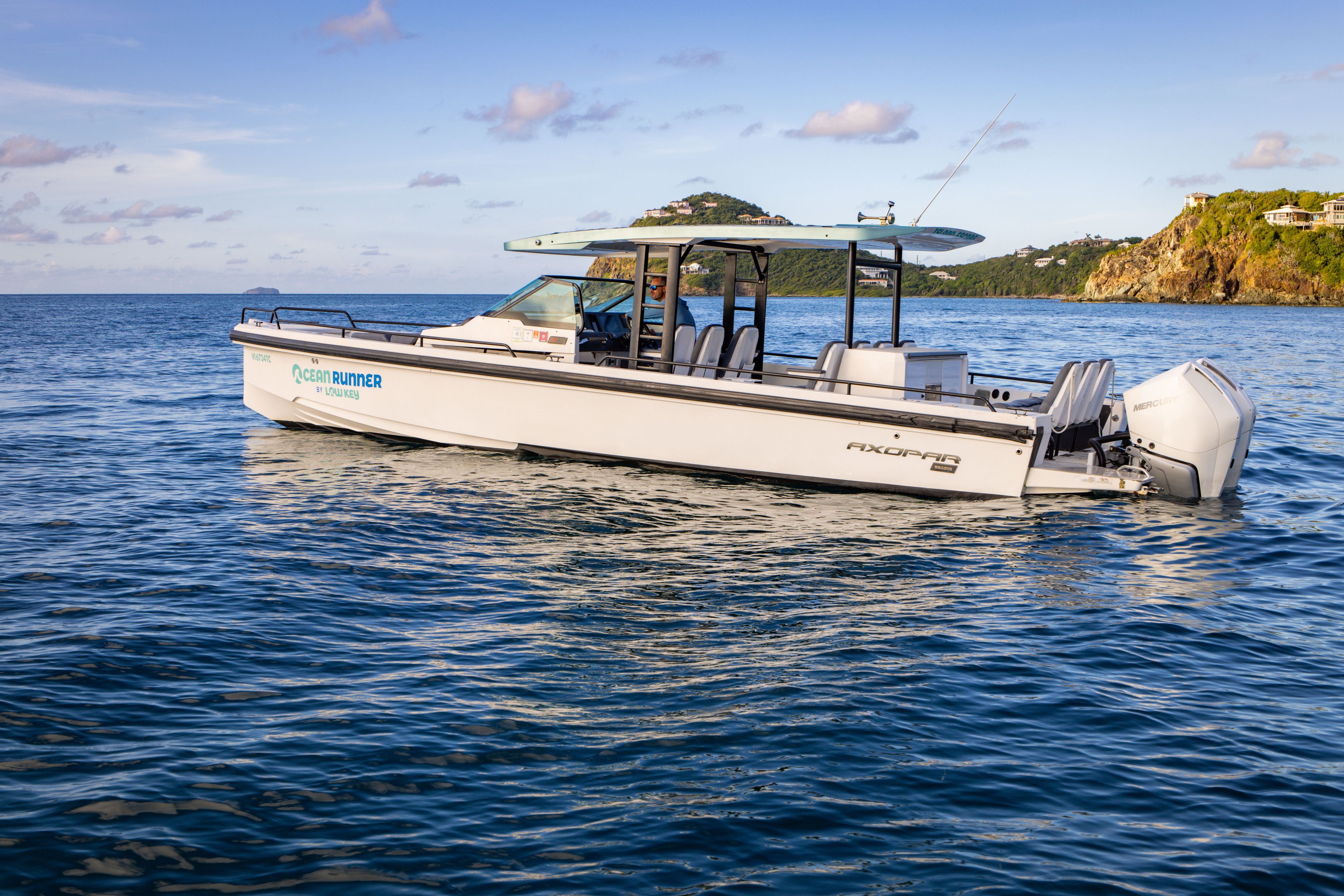 2020 Axopar 37 SUN TOP on calm water near a rocky coastline.