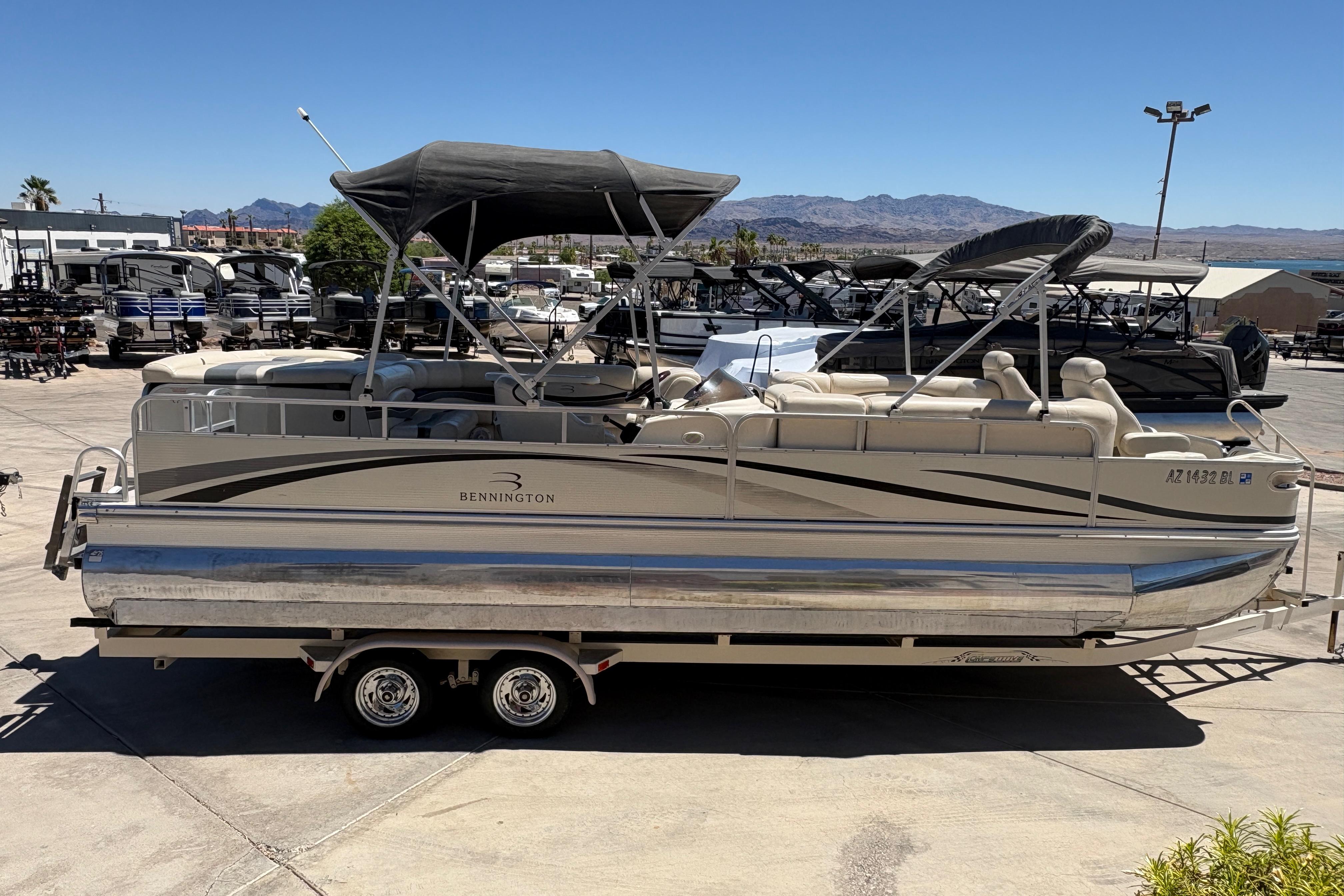 2005 Bennington 2575RFS I/O pontoon boat on trailer, parked in a marina under clear blue sky.