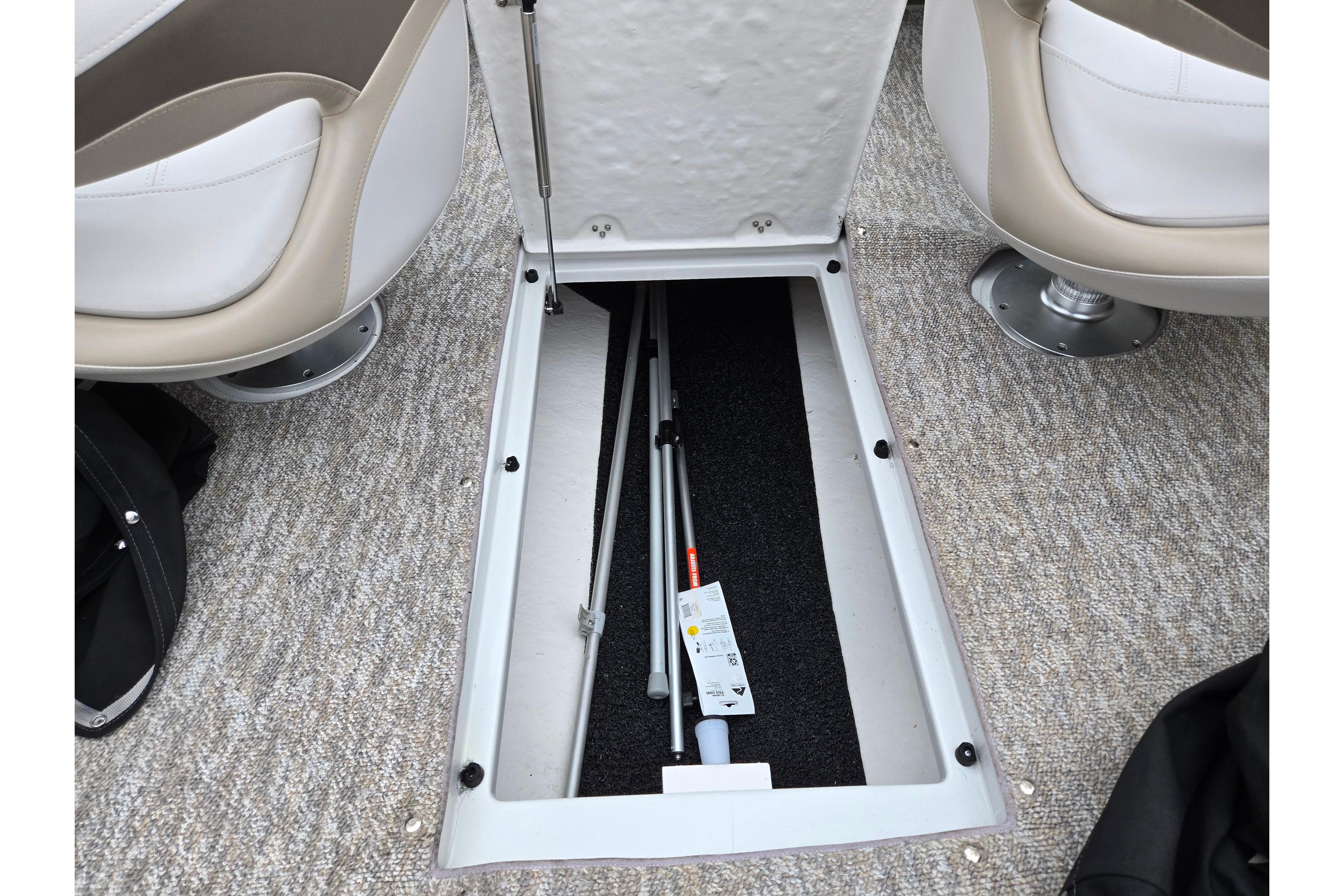 2012 Crownline 235 SS boat interior storage compartment with open hatch and equipment inside.