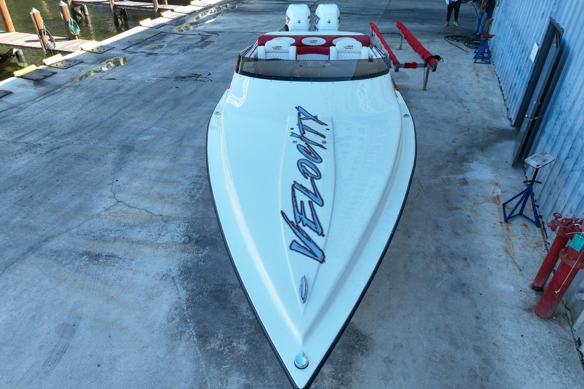 2022 Velocity 290sc speedboat on concrete dock, showcasing sleek design and branding.