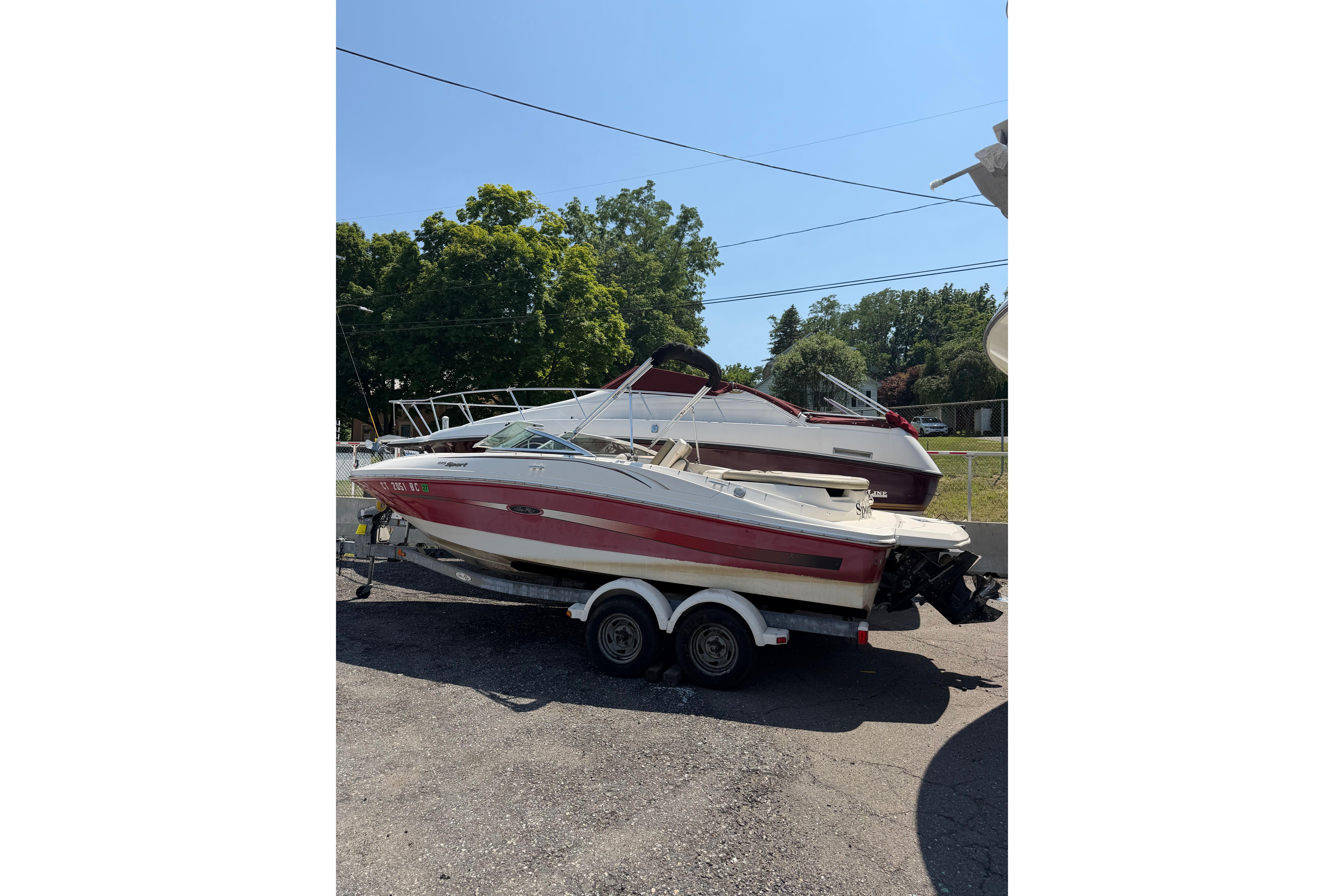 2006 Sea Ray 195 Sport boat on trailer, parked outdoors under clear sky.