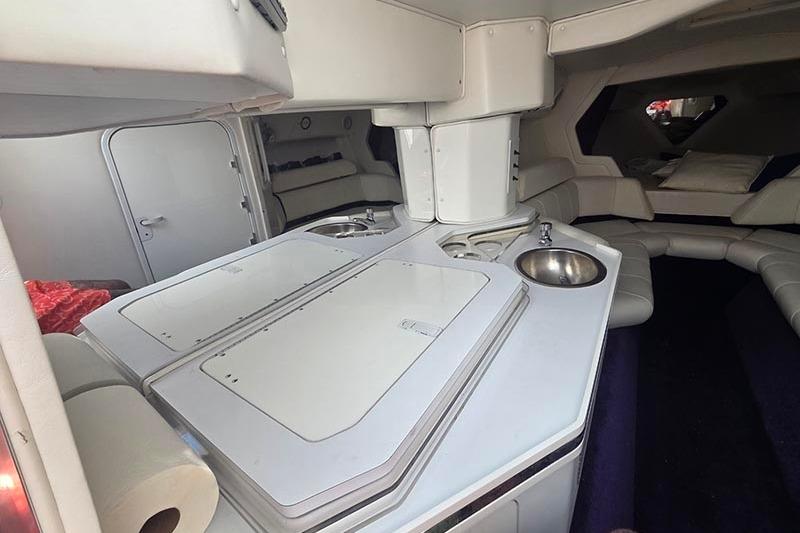 Interior of a 2004 Fountain 38 Lightning boat, featuring a compact kitchenette and seating area.