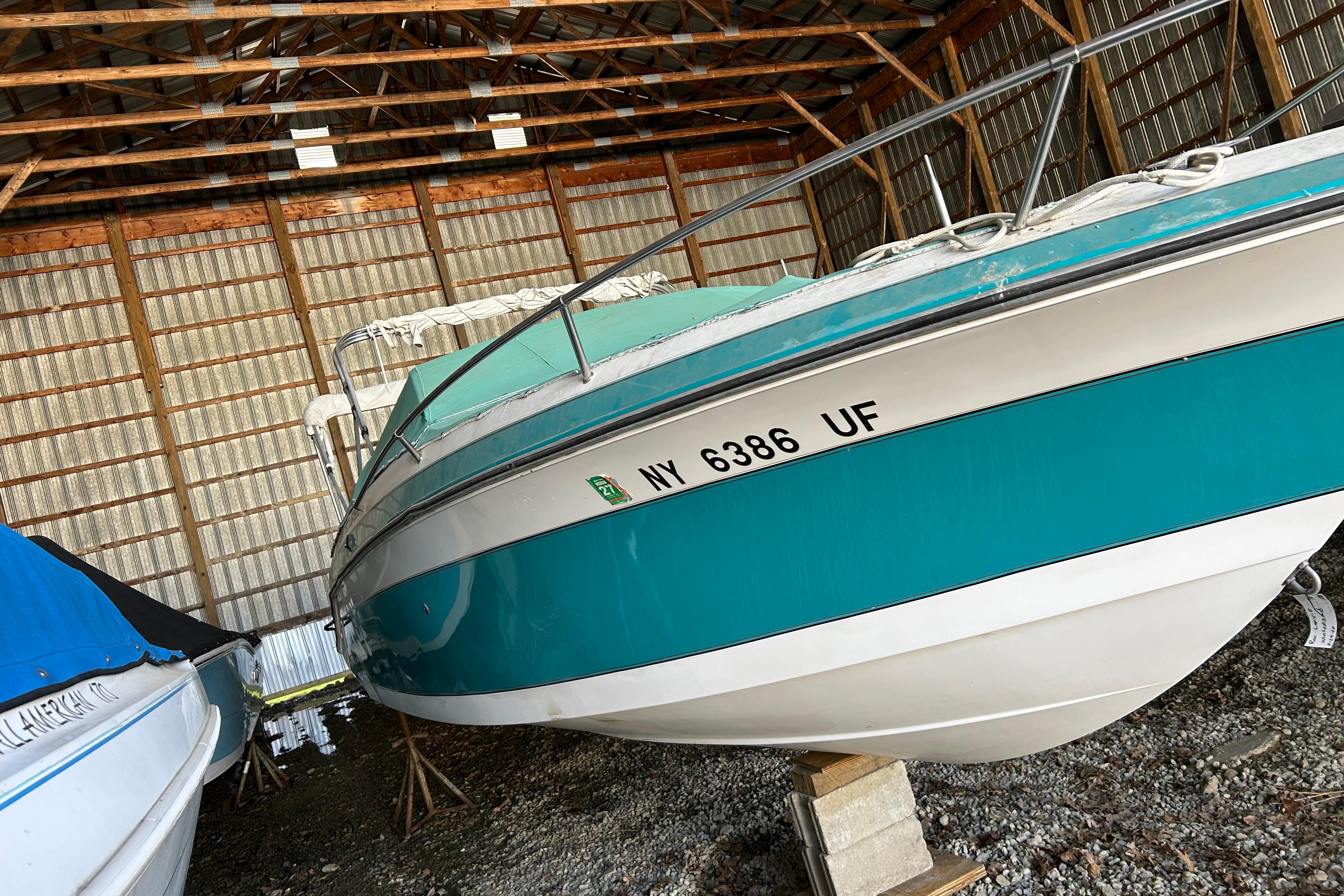 1991 Wellcraft 232 Eclipse boat stored indoors, teal and white exterior.