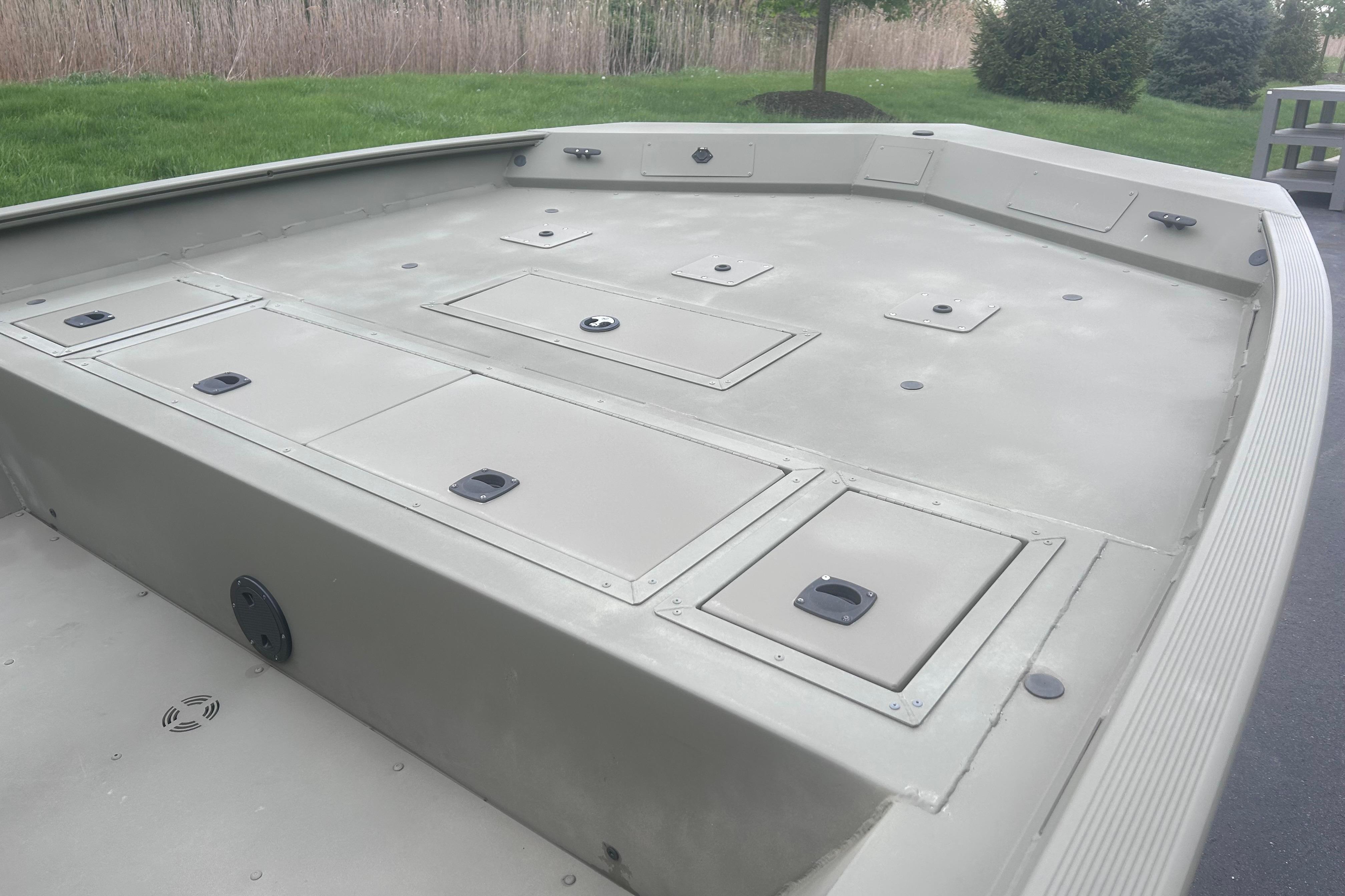 2024 Tracker Grizzly 2072 CC boat deck with storage compartments, set in a grassy outdoor area.