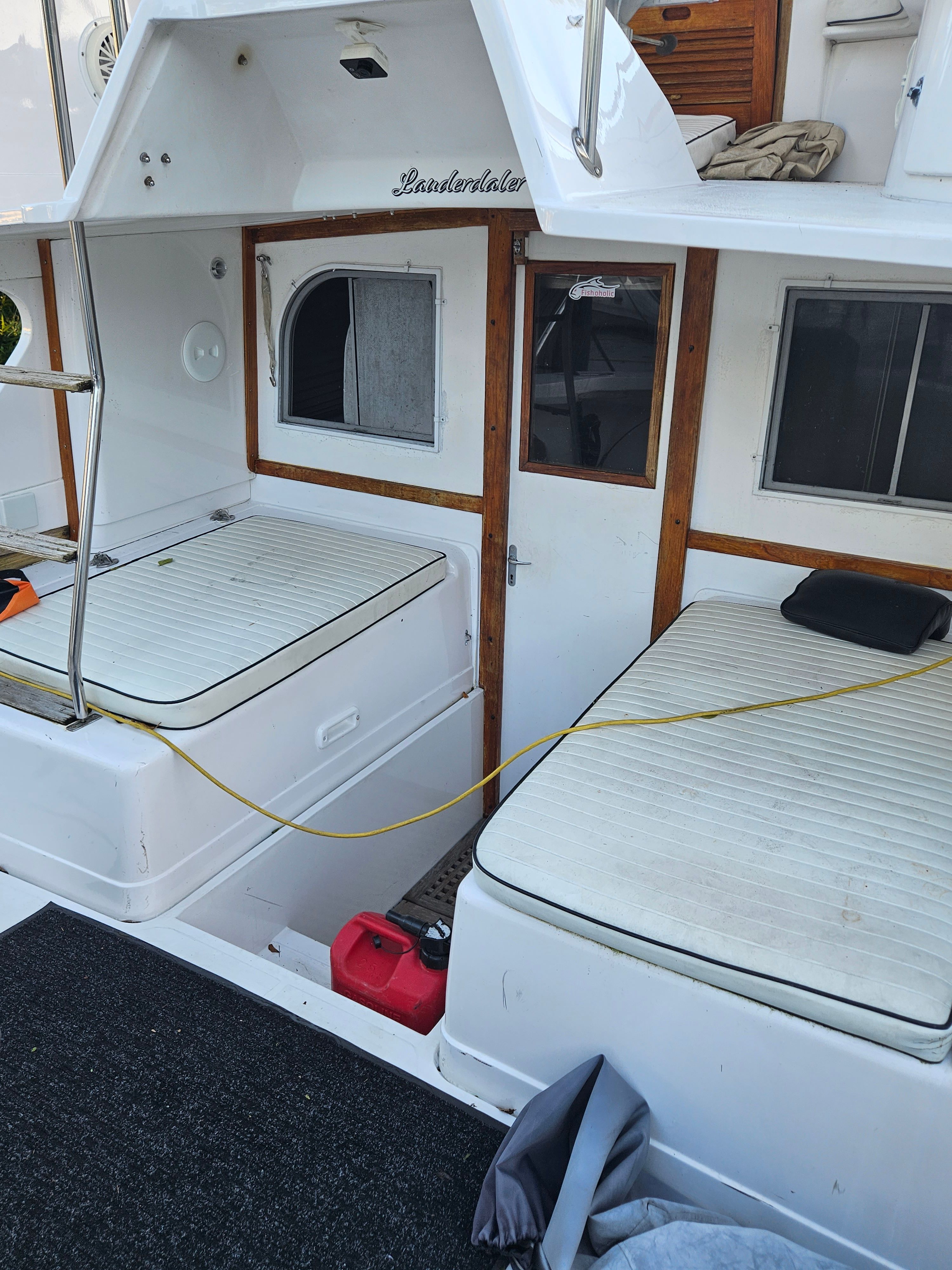 The image shows the stern of a boat with two cushioned seating areas and wooden accents.