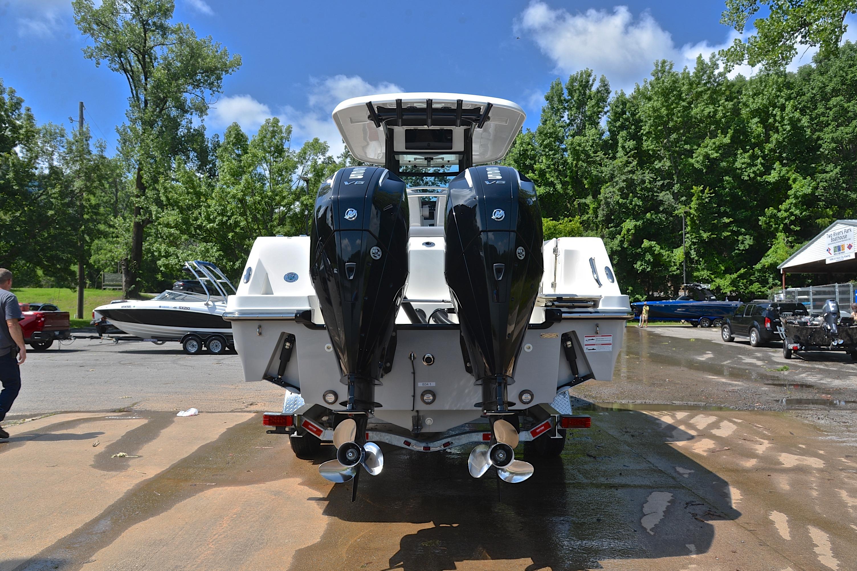 2024 Boston Whaler 250 Outrage with dual outboard engines, parked outdoors on a sunny day.