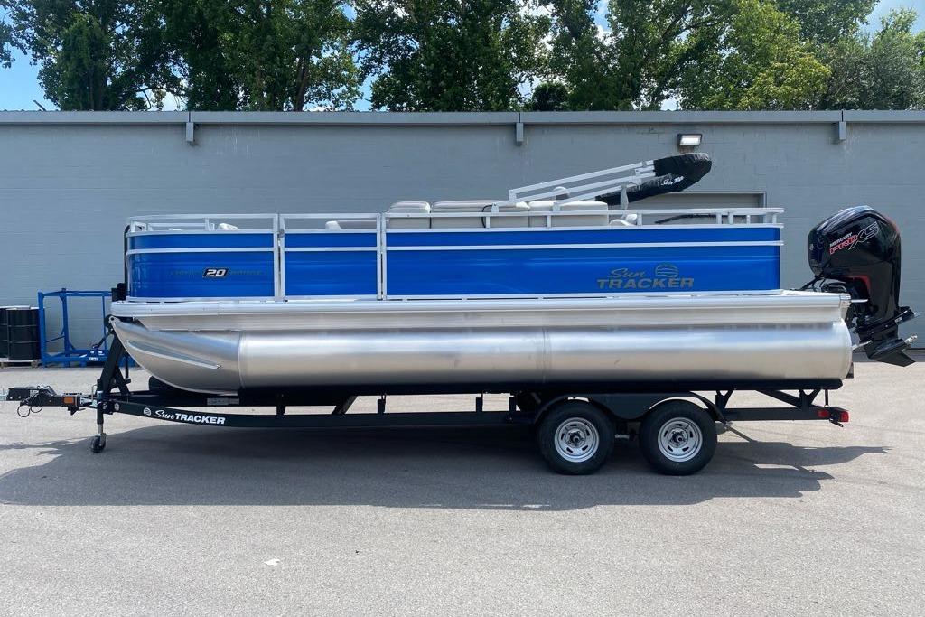2026 Sun Tracker Fishin' Barge 20 DLX pontoon boat on trailer, parked outdoors.