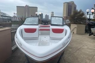 2025 Tahoe 200 S boat with red and white seating, docked near urban buildings.
