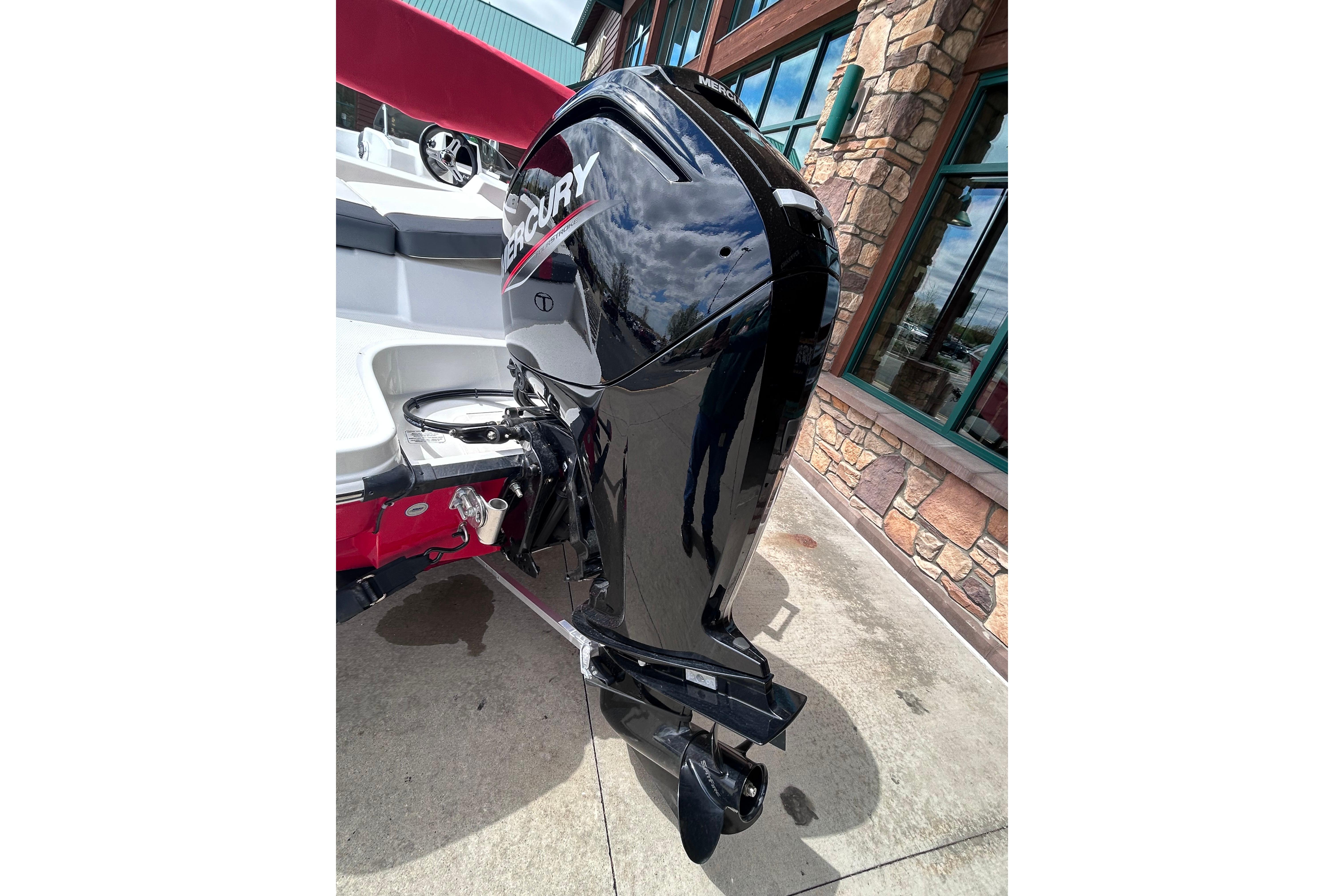 2026 Tahoe T16 boat with Mercury outboard motor, parked on concrete near a building.