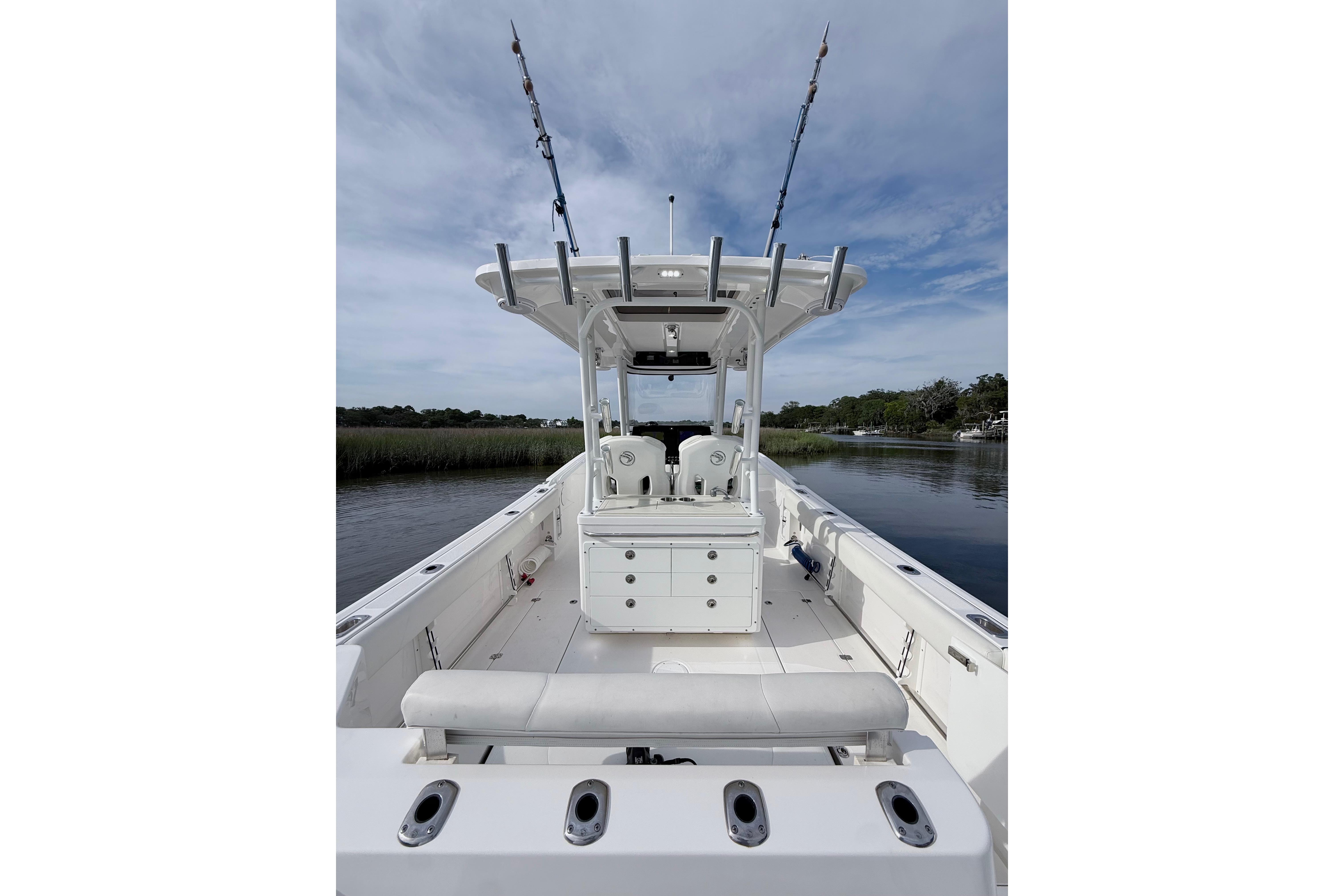 2022 Edgewater 280CC boat with fishing rods, spacious deck, and serene water backdrop.