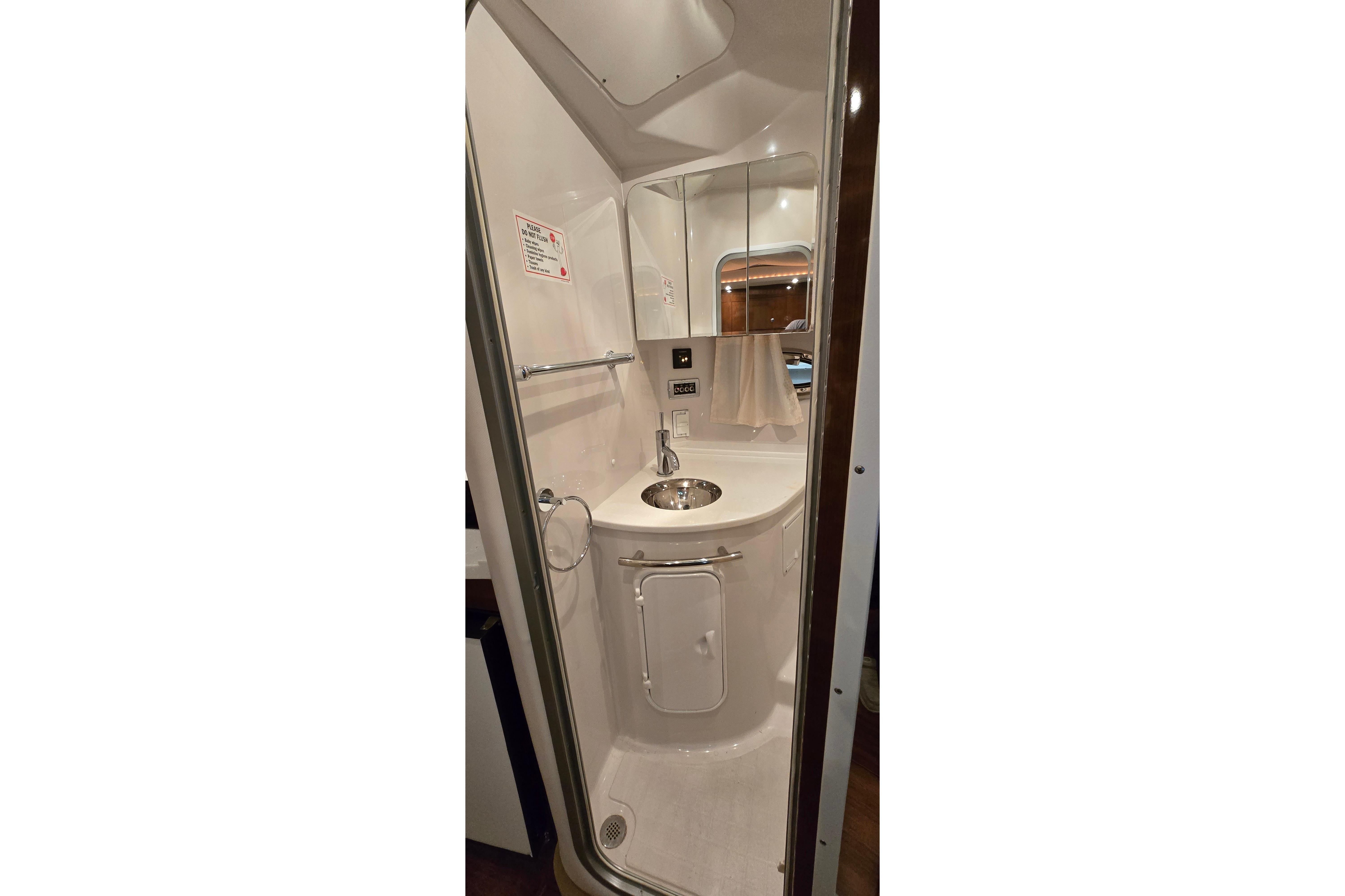 Compact bathroom in 2018 Four Winns V355 boat, featuring a sleek sink and mirror.