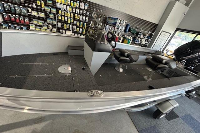2027 Lund 1600 Fury SS boat interior with seating and control console in showroom.