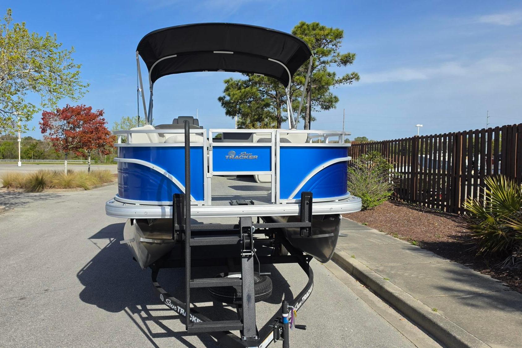 2026 Sun Tracker Fishin' Barge 20 DLX pontoon boat on trailer, parked outdoors.