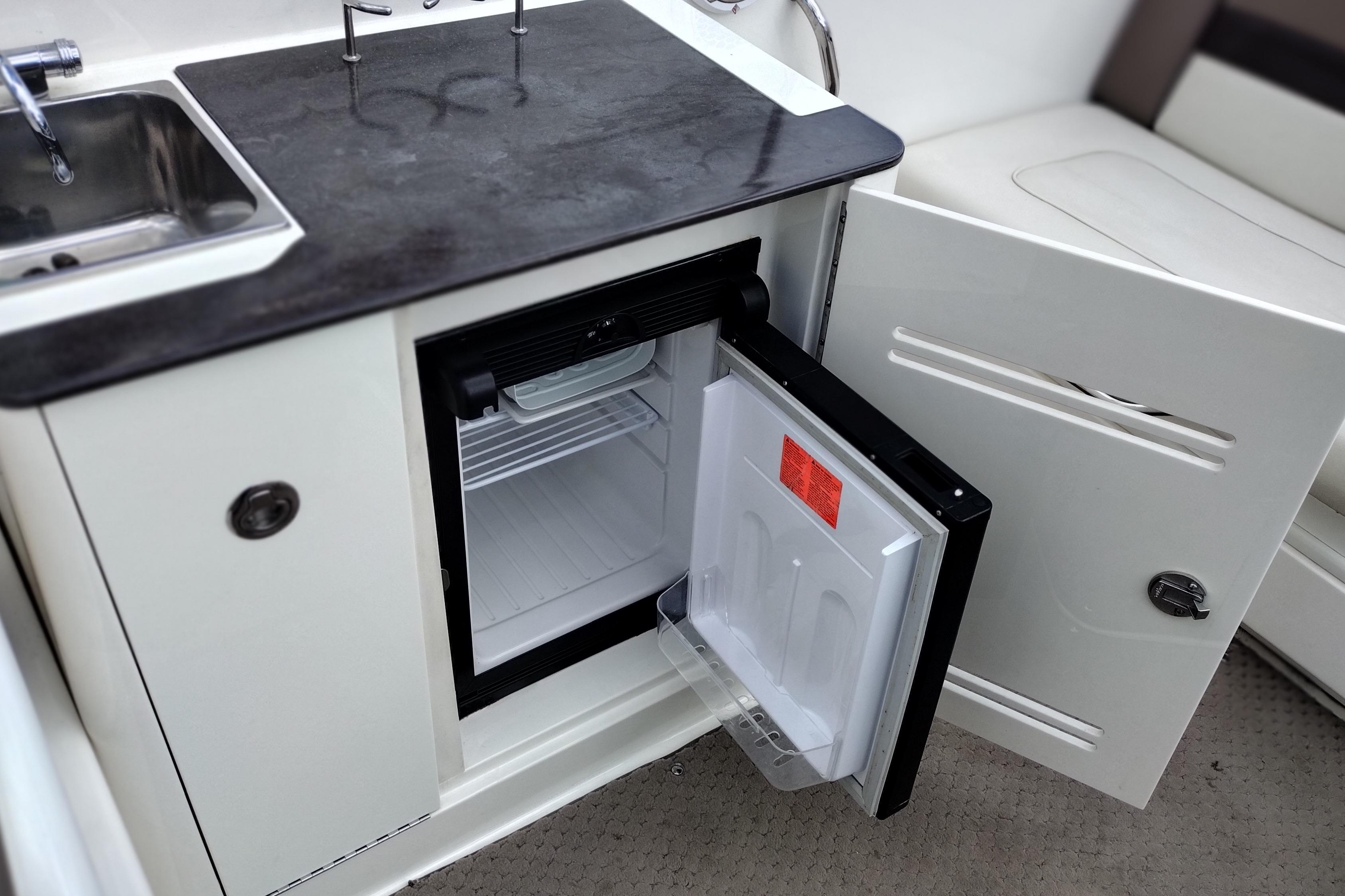 2013 Sea Ray 300 SLX boat kitchenette with open mini fridge and sink.