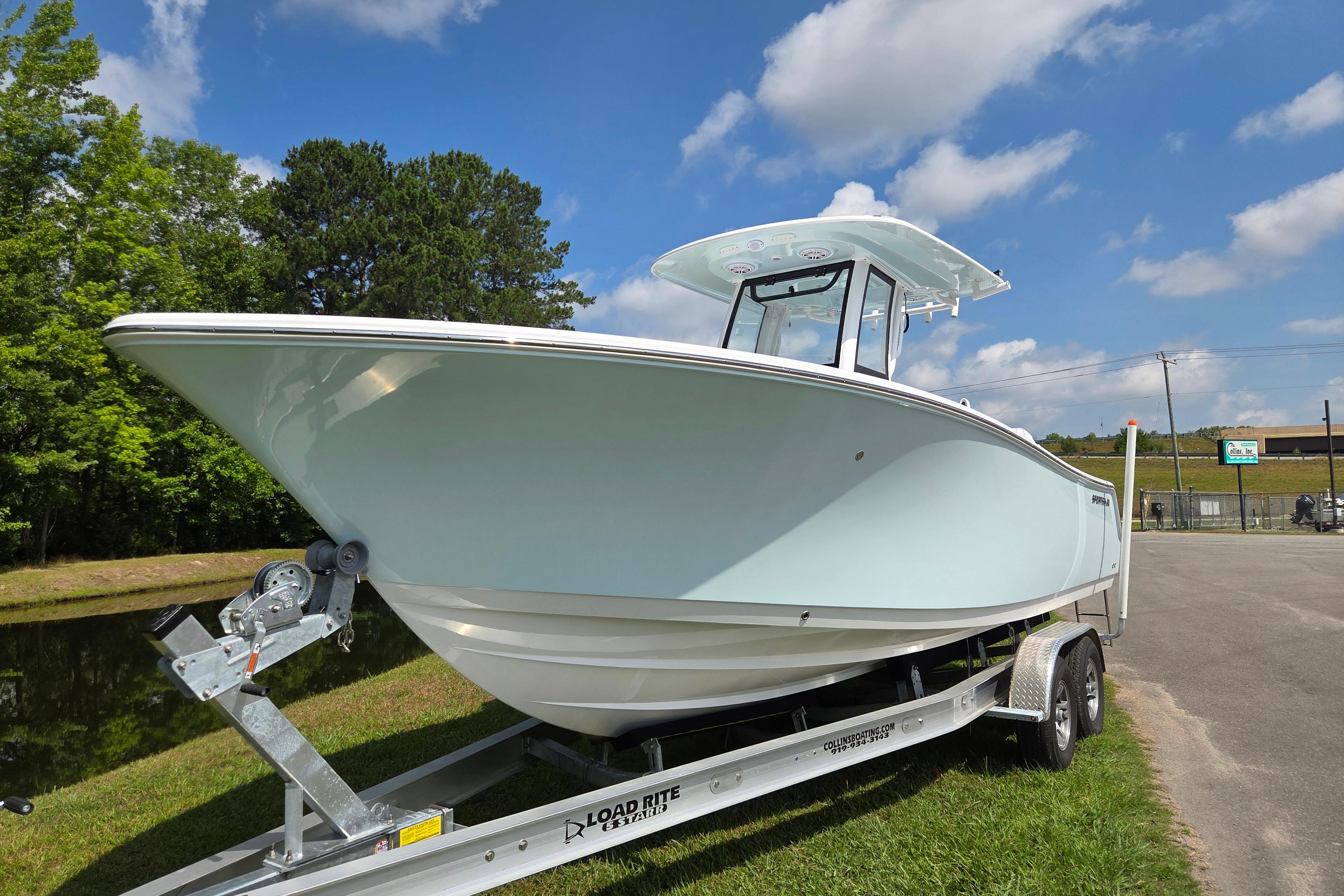 2026 Sportsman Open 252 Center Console boat on trailer, parked outdoors under blue sky.