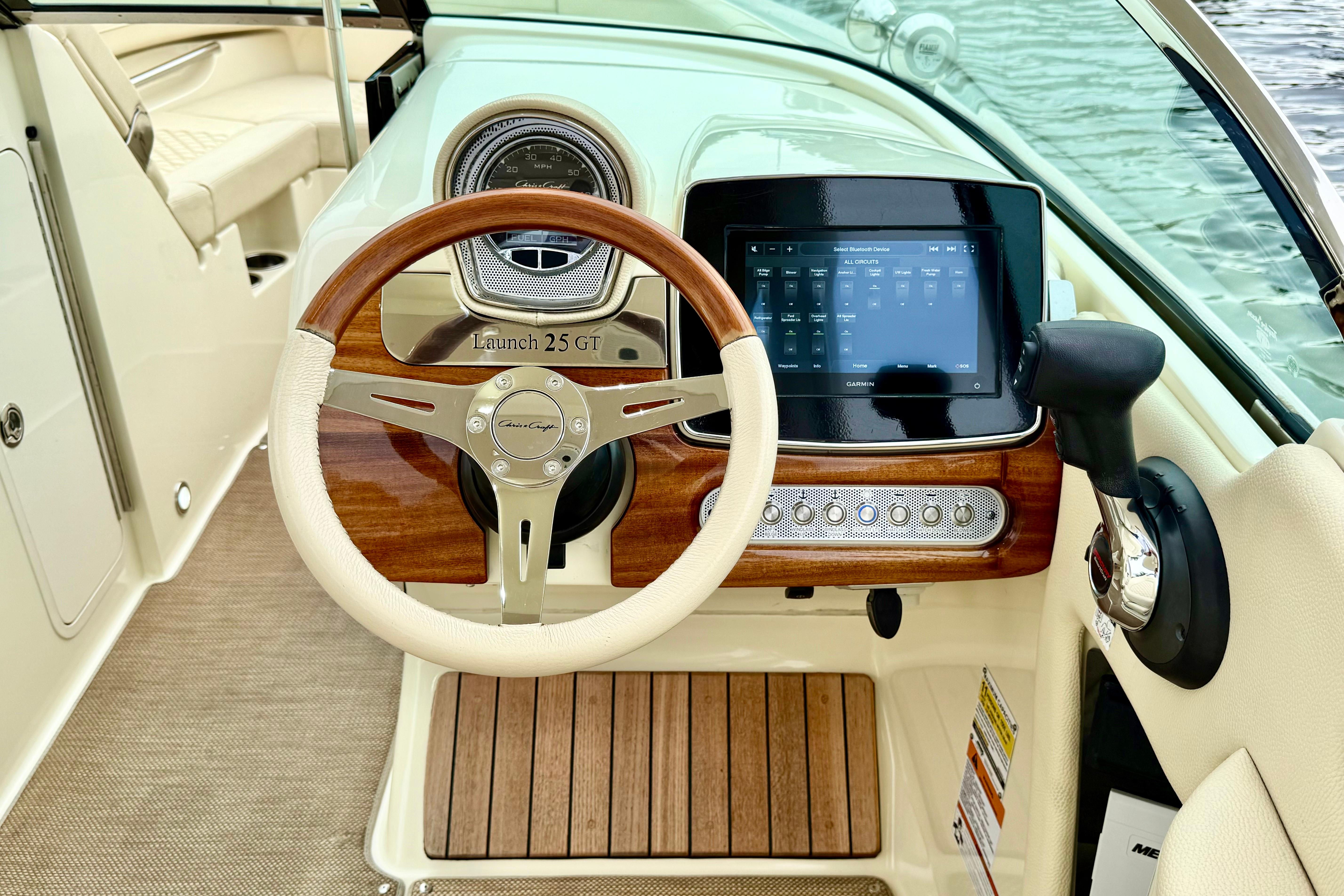 2022 Chris-Craft Launch 25 GT dashboard with wooden steering wheel and digital display.