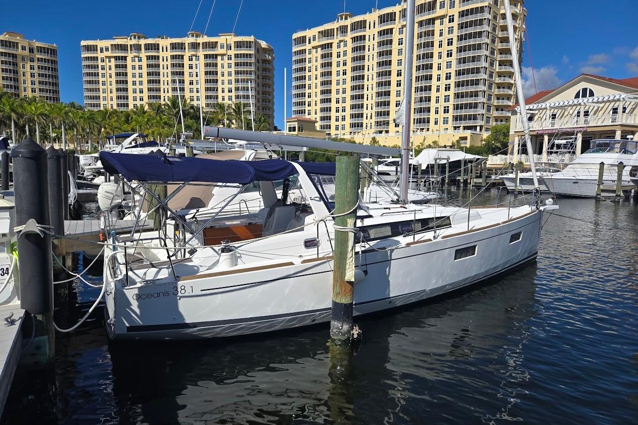 2023 Beneteau Oceanis 38.1 yacht docked at marina with luxury buildings in background.