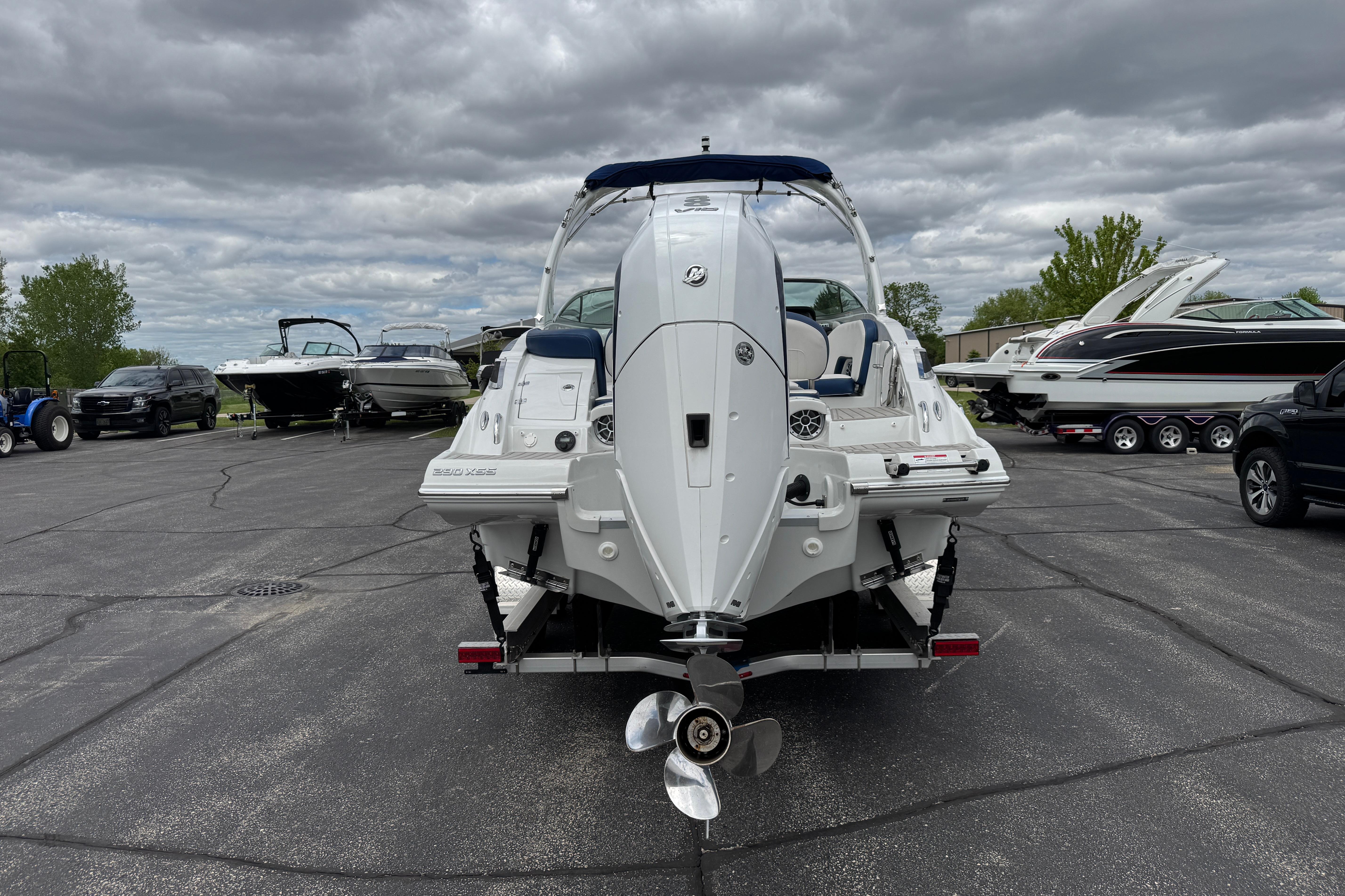 2025 Crownline 290 XSS boat on trailer, parked in a marina lot under cloudy skies.