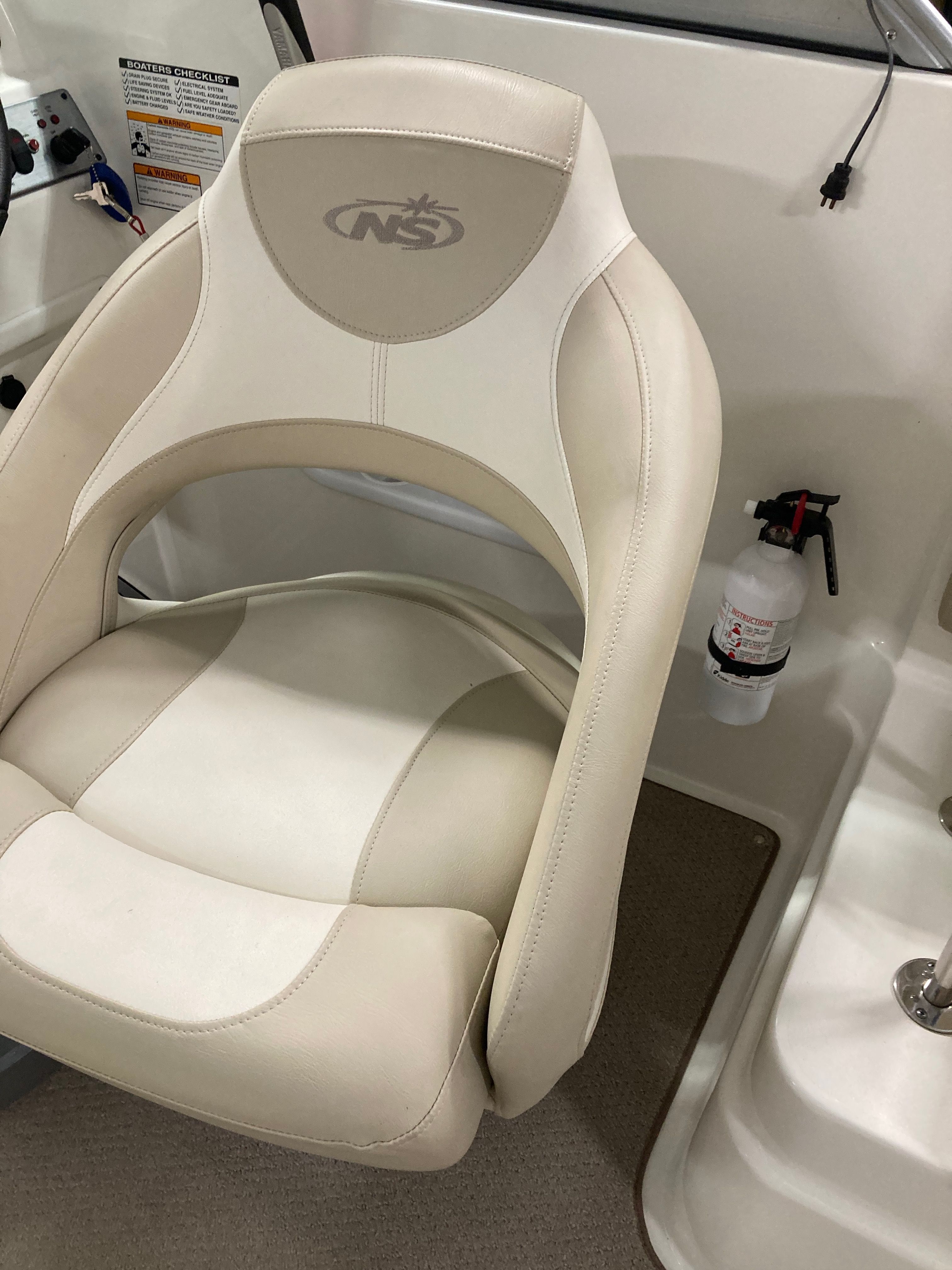 Boat seat with beige upholstery and a fire extinguisher beside it.