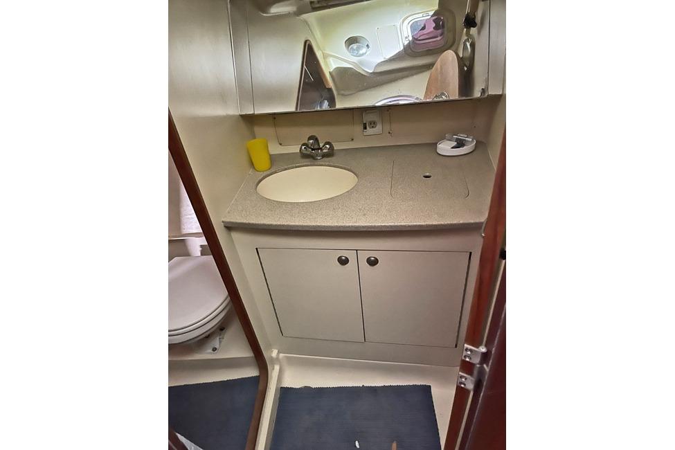 1999 Hunter 380 yacht bathroom with sink, mirror, and storage cabinets.