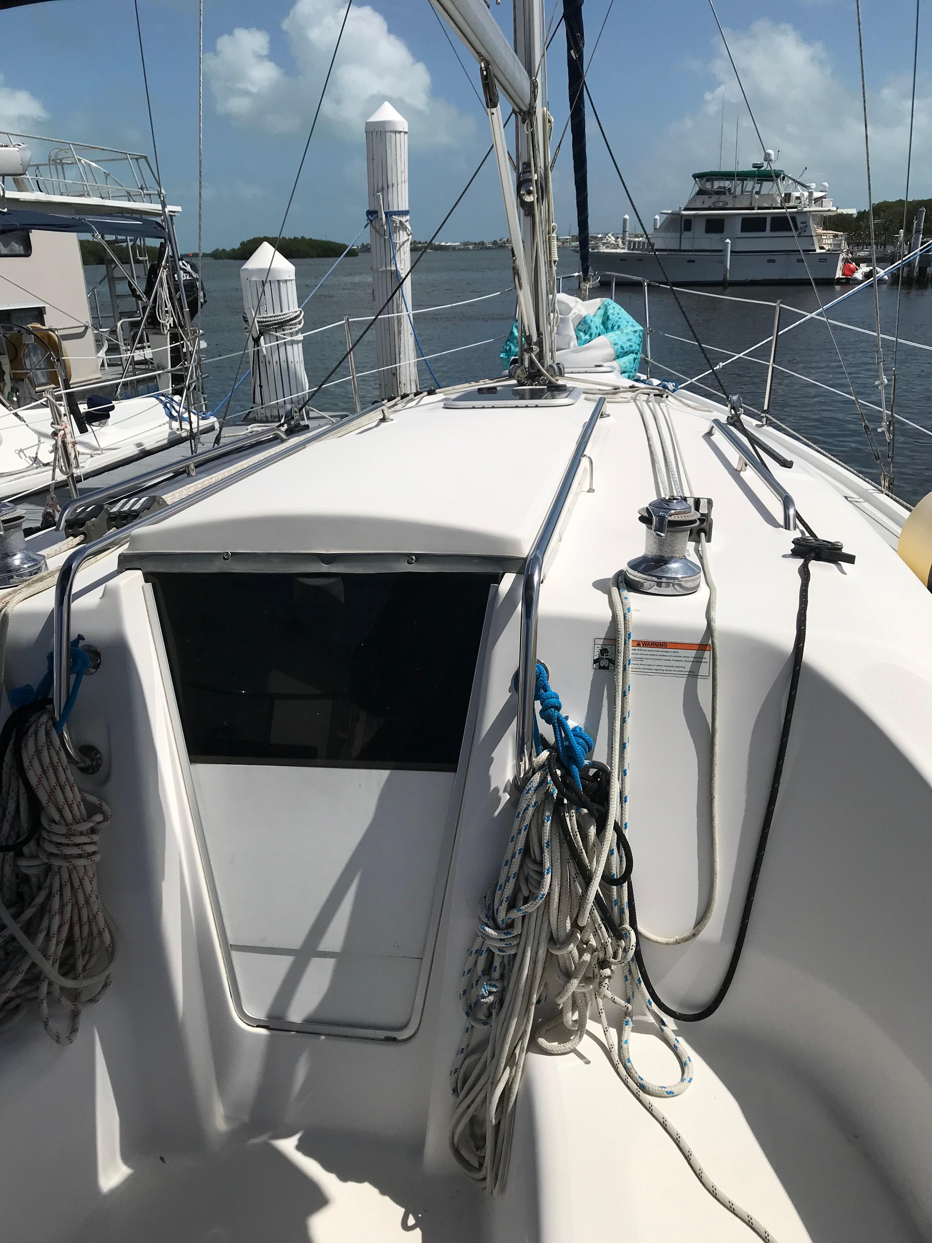 2009 Hunter 310 sailboat deck with ropes and winch, docked in a marina.