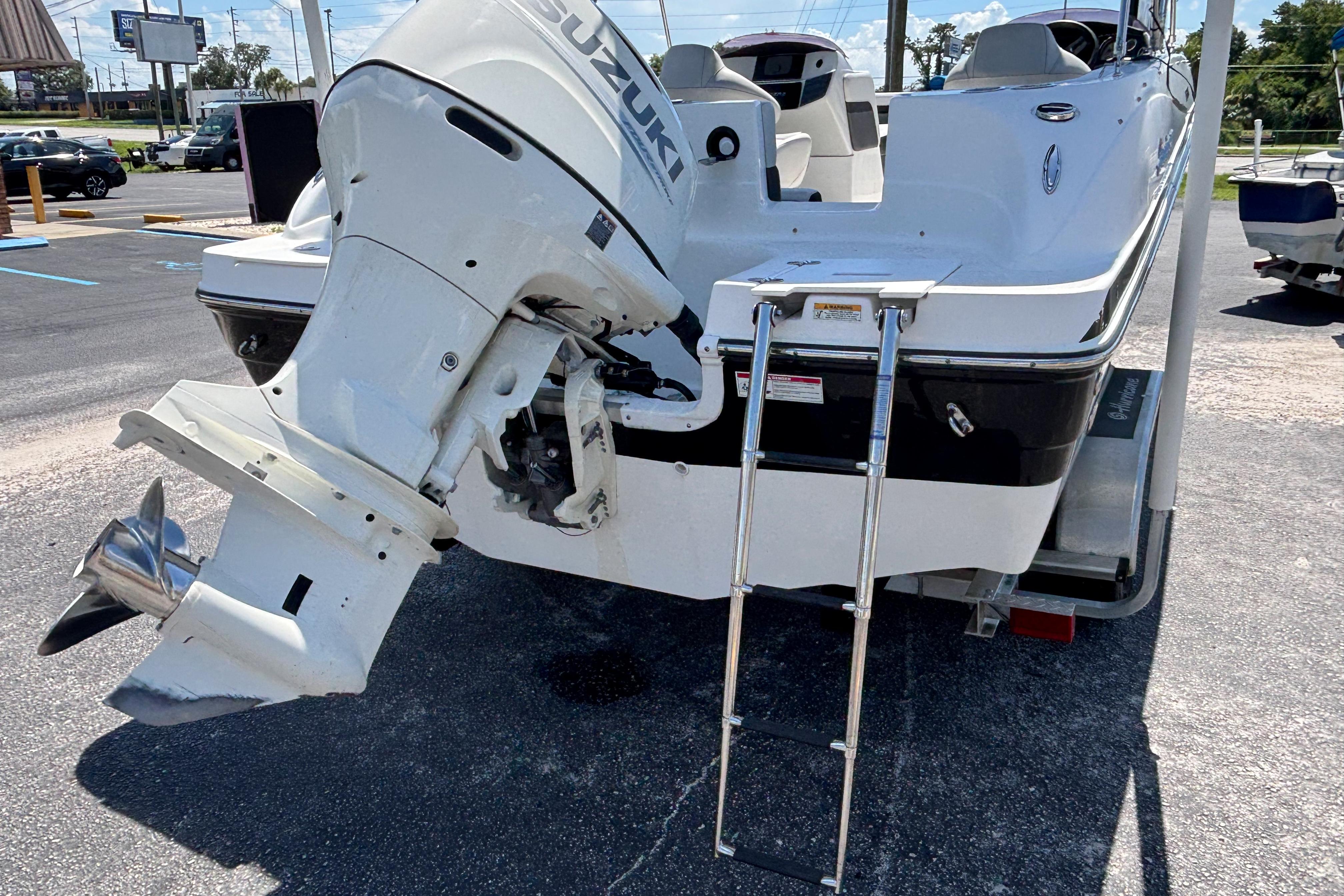 2019 Hurricane Sundeck Sport 218 OB with Suzuki outboard motor and ladder on trailer.