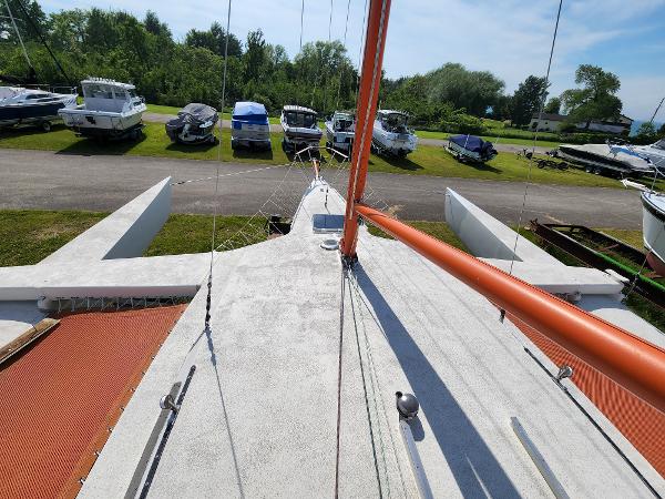1985 Crowther Buccaneer sailboat on land, surrounded by parked boats and greenery.